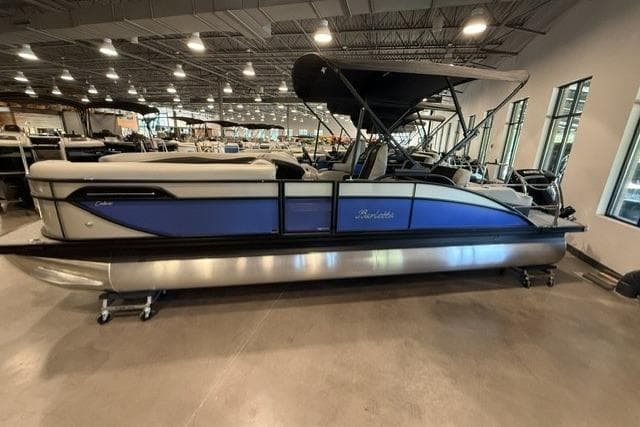 2026 Barletta Cabrio 24UC pontoon boat displayed indoors with blue and silver design.