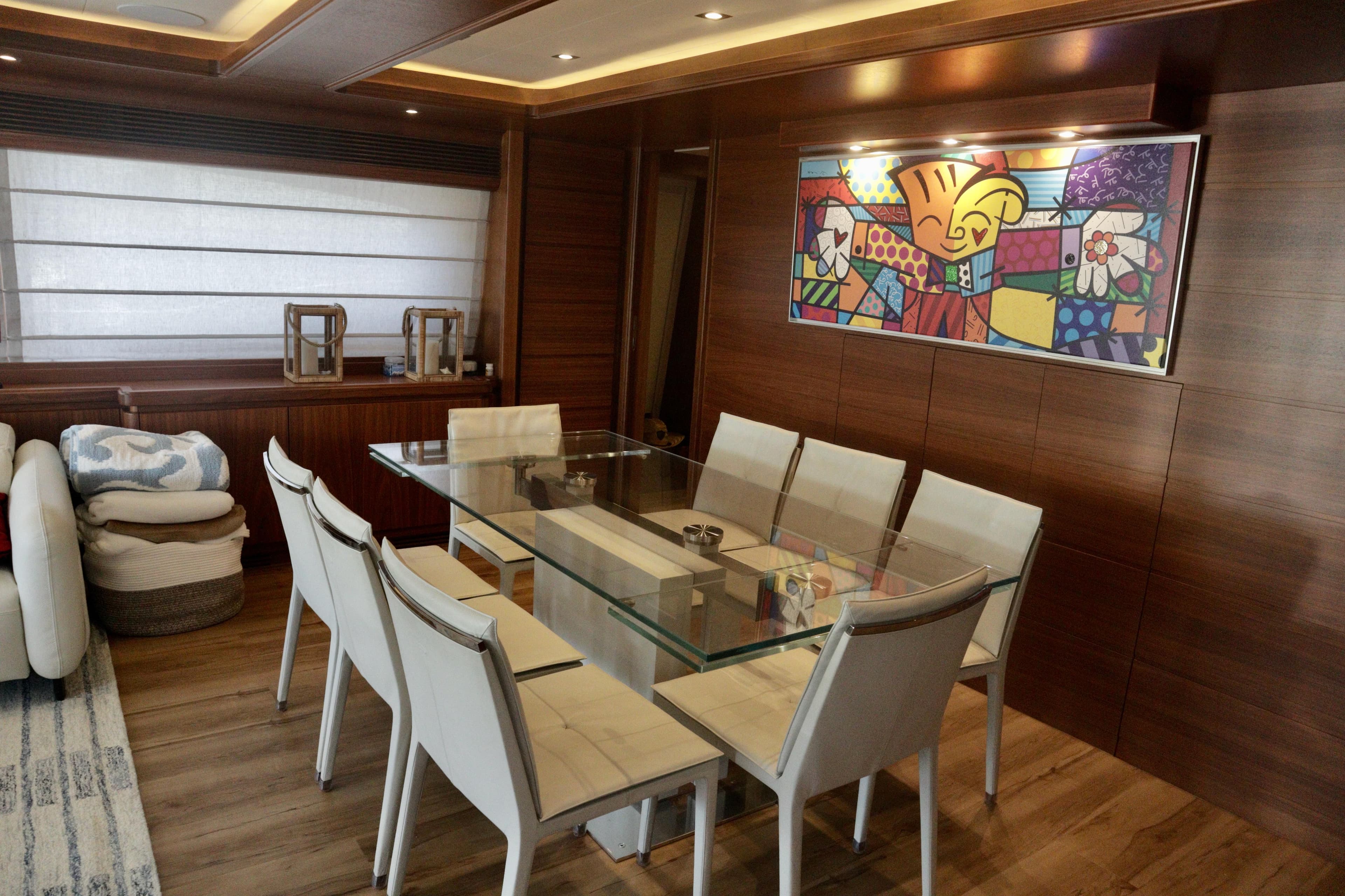 Luxurious dining area on 2016 Custom Line 97 yacht with modern decor and glass table.