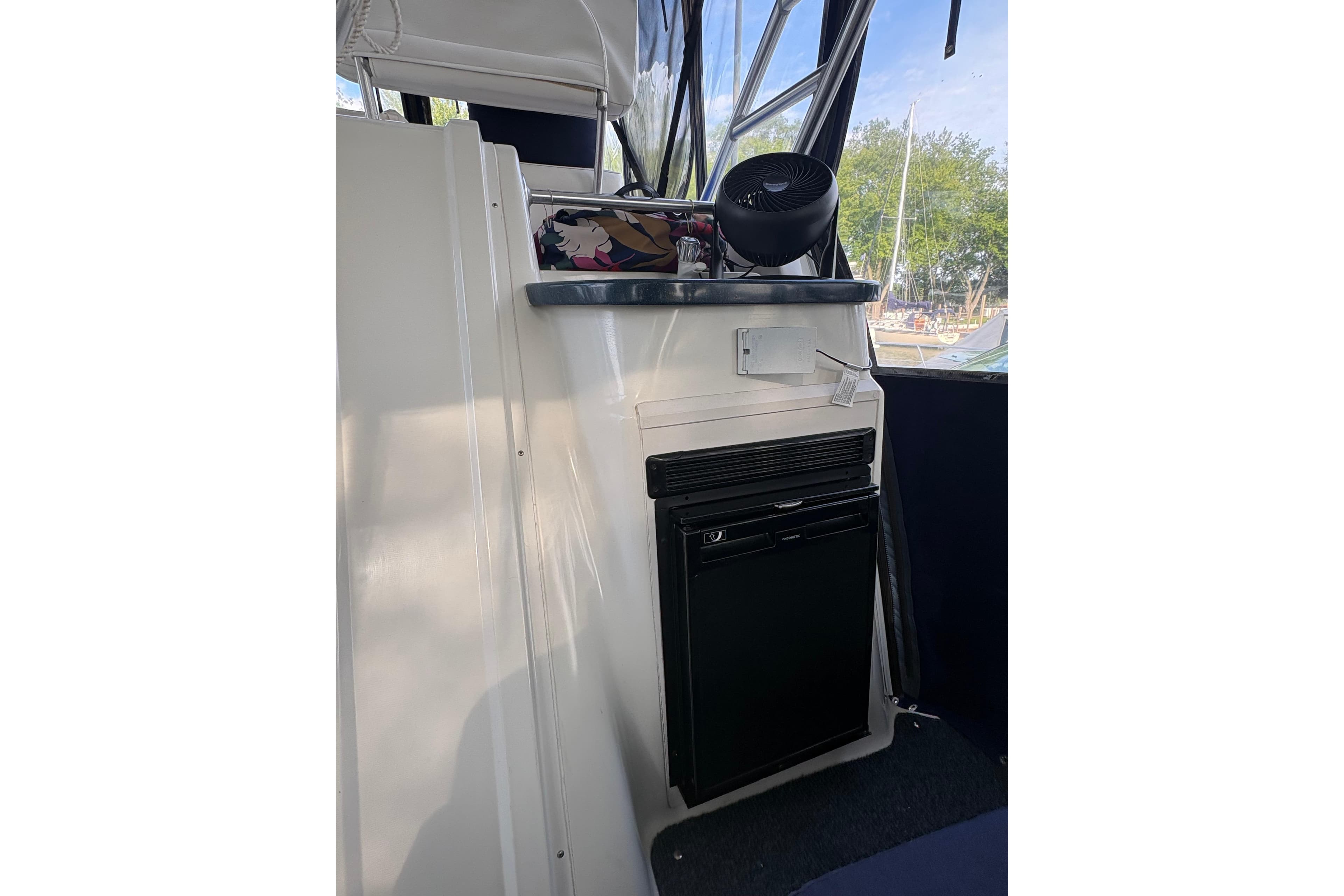 Interior view of 1997 Mainship 34 Motor Yacht with compact fridge and fan.