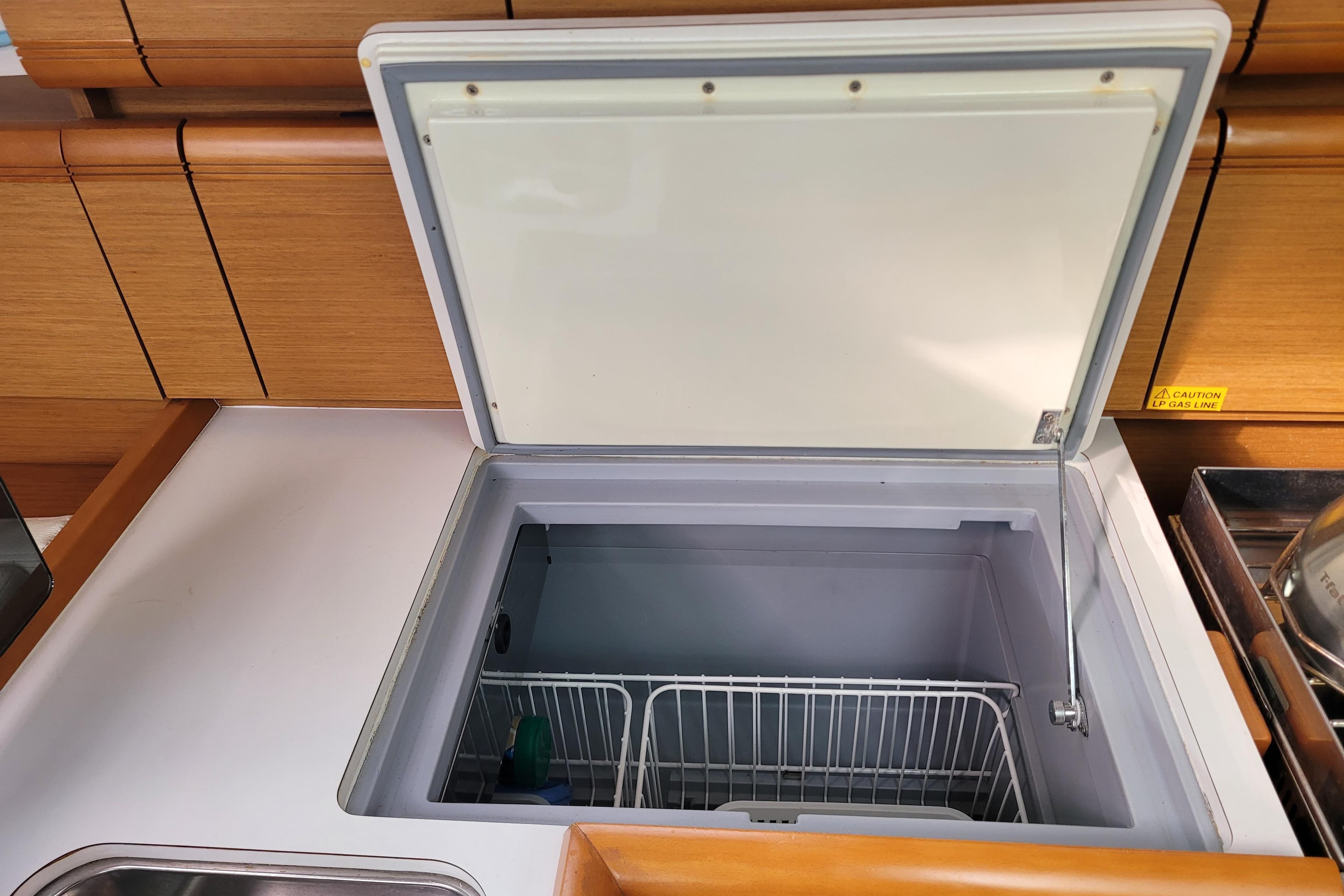 Open freezer compartment in 2014 Jeanneau 379 yacht kitchen, featuring wooden cabinetry.