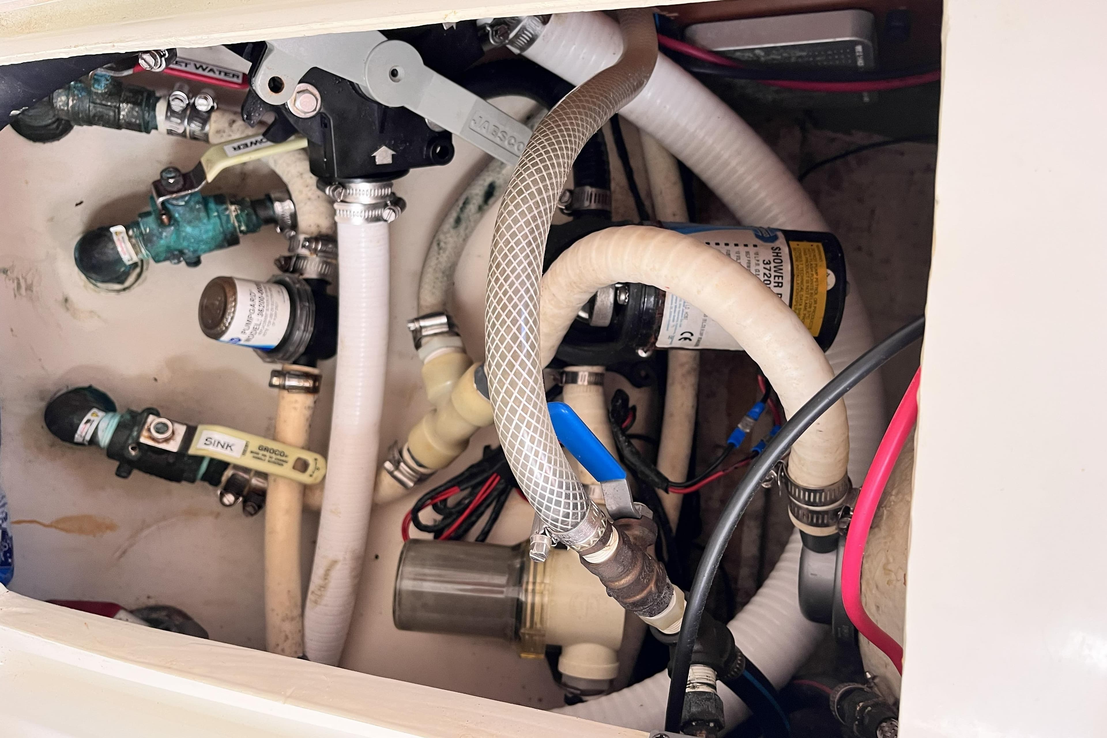 Plumbing system inside a 2001 Beneteau 473 yacht, featuring hoses and valves.