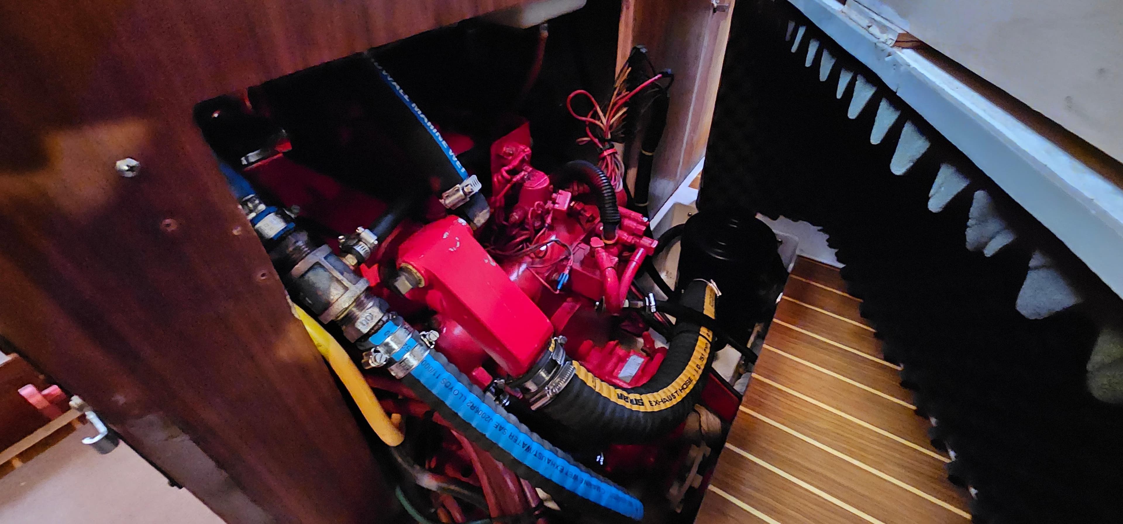 Engine compartment of a 1995 Catalina 400 sailboat, featuring red engine components and hoses.