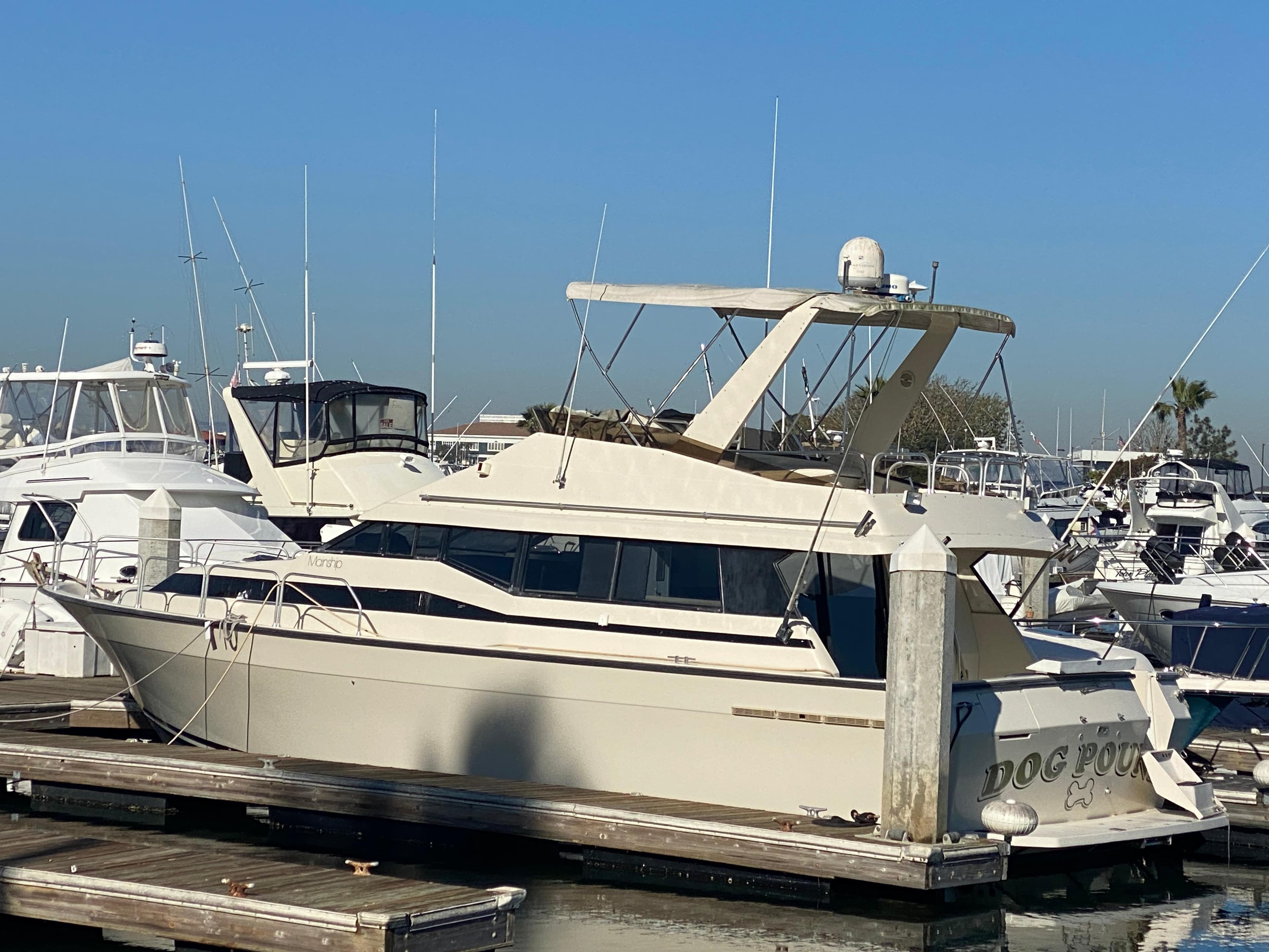 1991 Mainship 41 Convertible yacht docked at marina under clear blue sky.