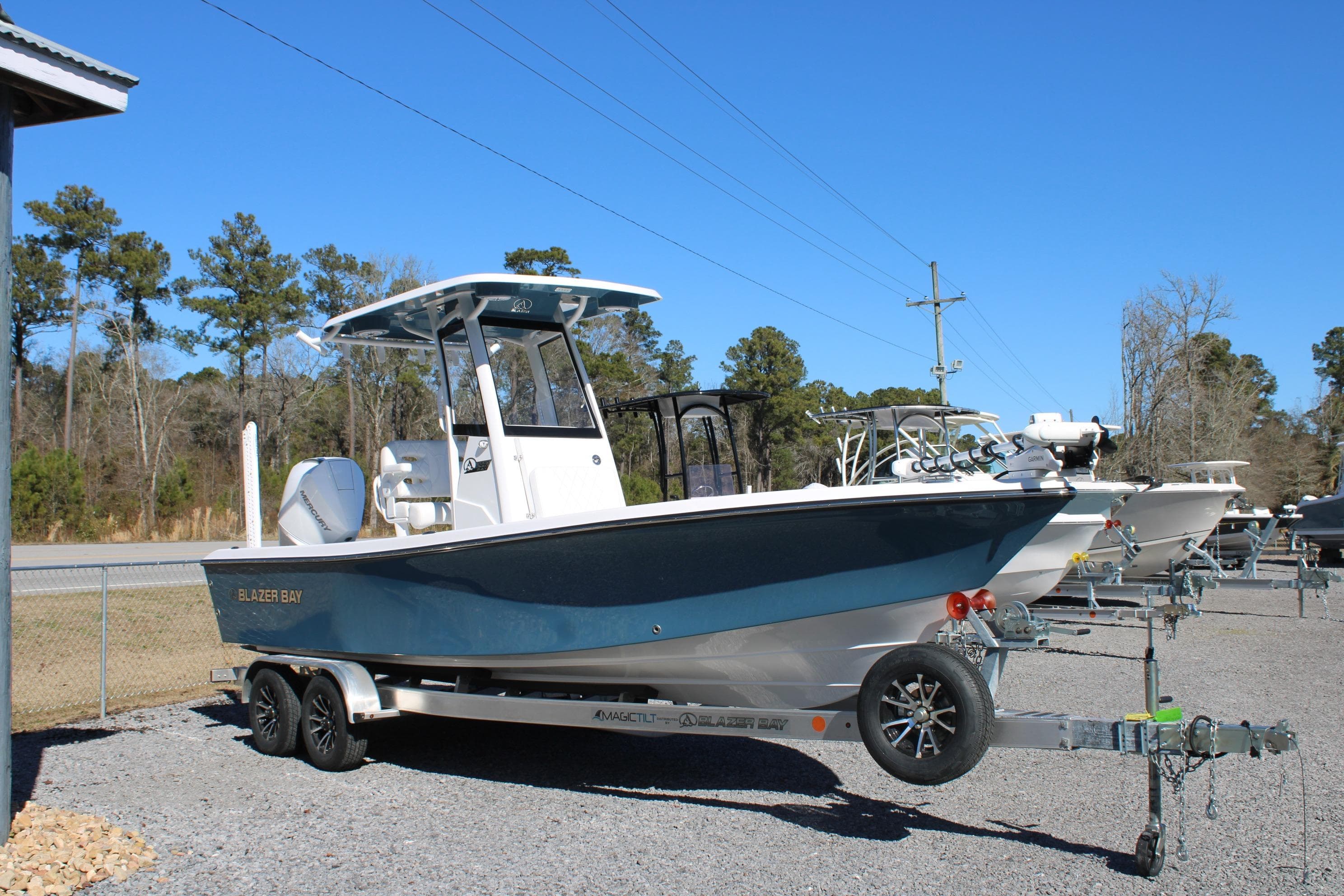 2026 Blazer Bay 2440 boat on trailer, parked outdoors under clear blue sky.