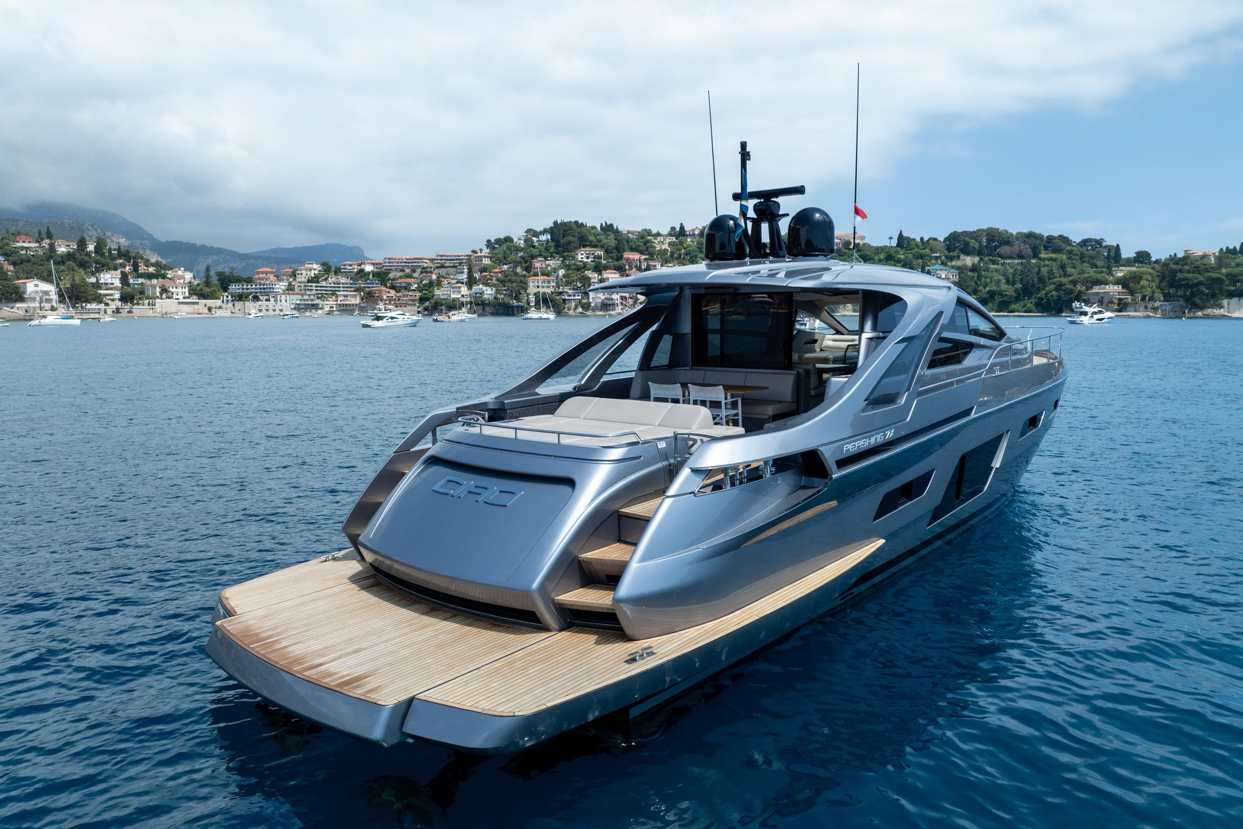 2024 Pershing 7X yacht on serene blue waters near coastal town.