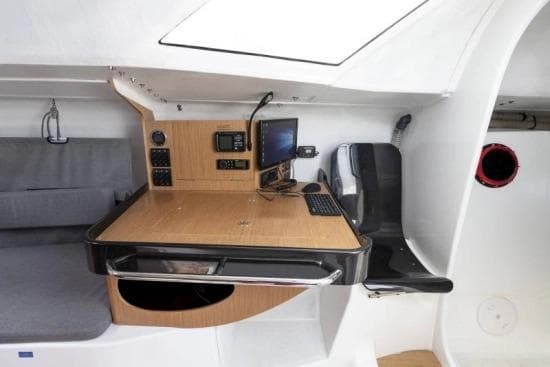 Navigation station inside 2024 Jeanneau Sun Fast 3300 yacht with control panel and seating.