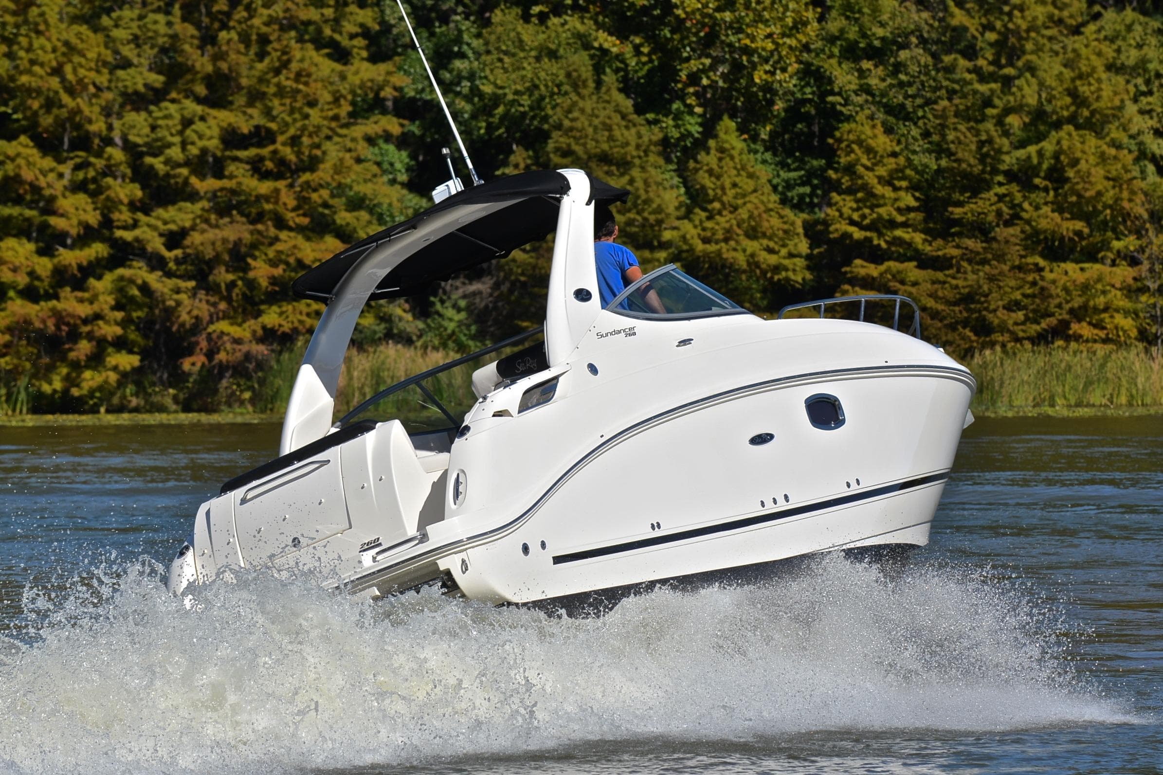 2011 Sea Ray 260 Sundancer cruising on a scenic lake with lush green trees.