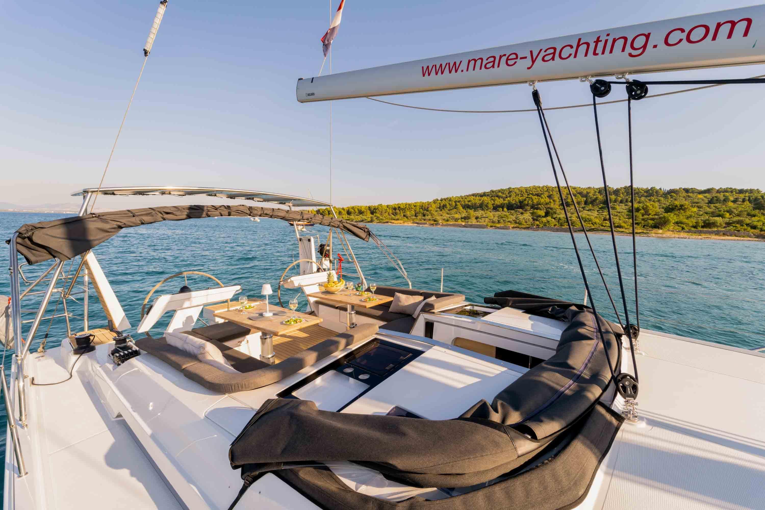 Luxurious 2025 Hanse 460 yacht sailing near scenic coastline, featuring spacious deck and modern amenities.