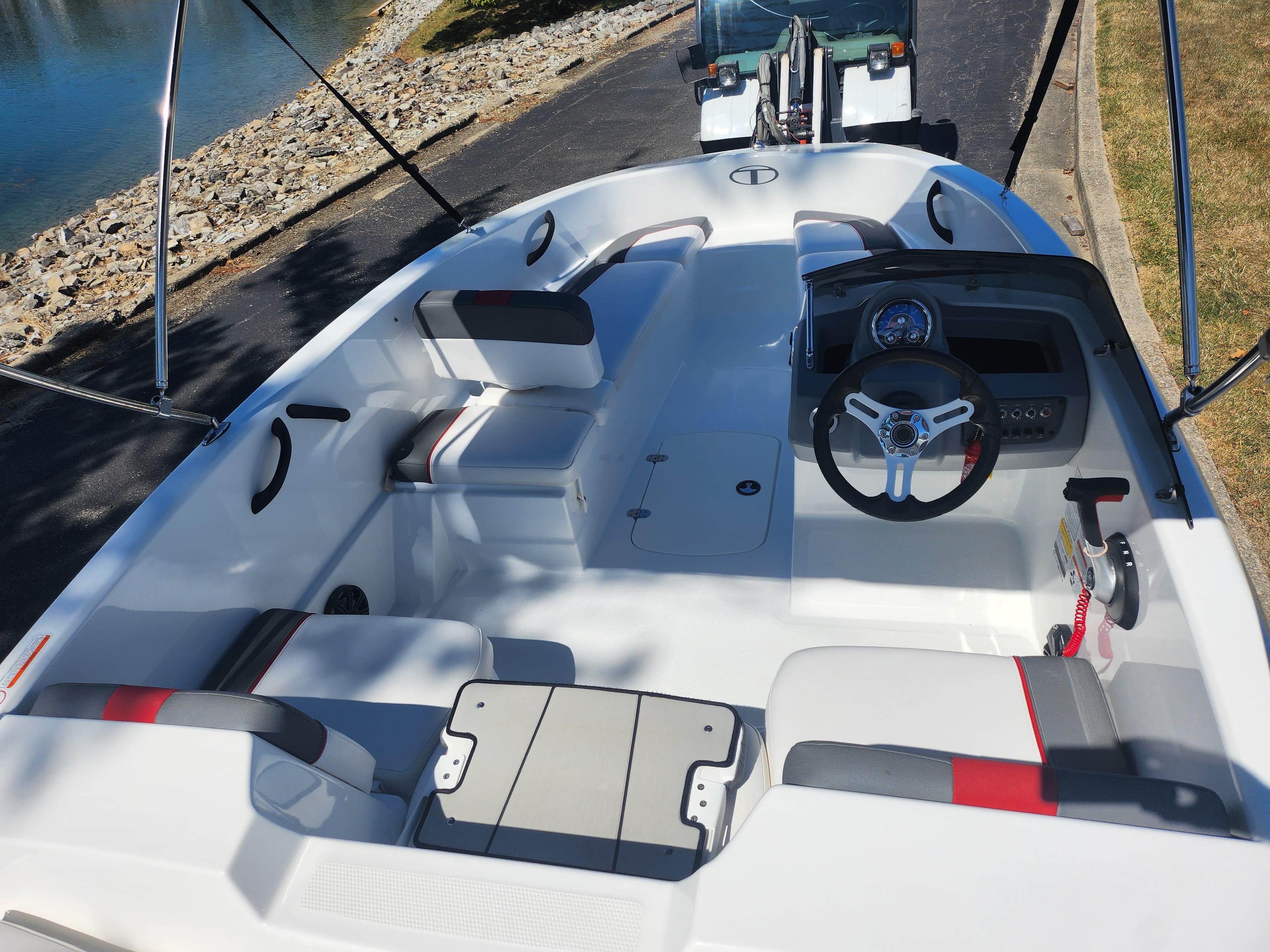 2021 Tahoe T16 boat interior with seating and steering wheel, parked near a waterway.