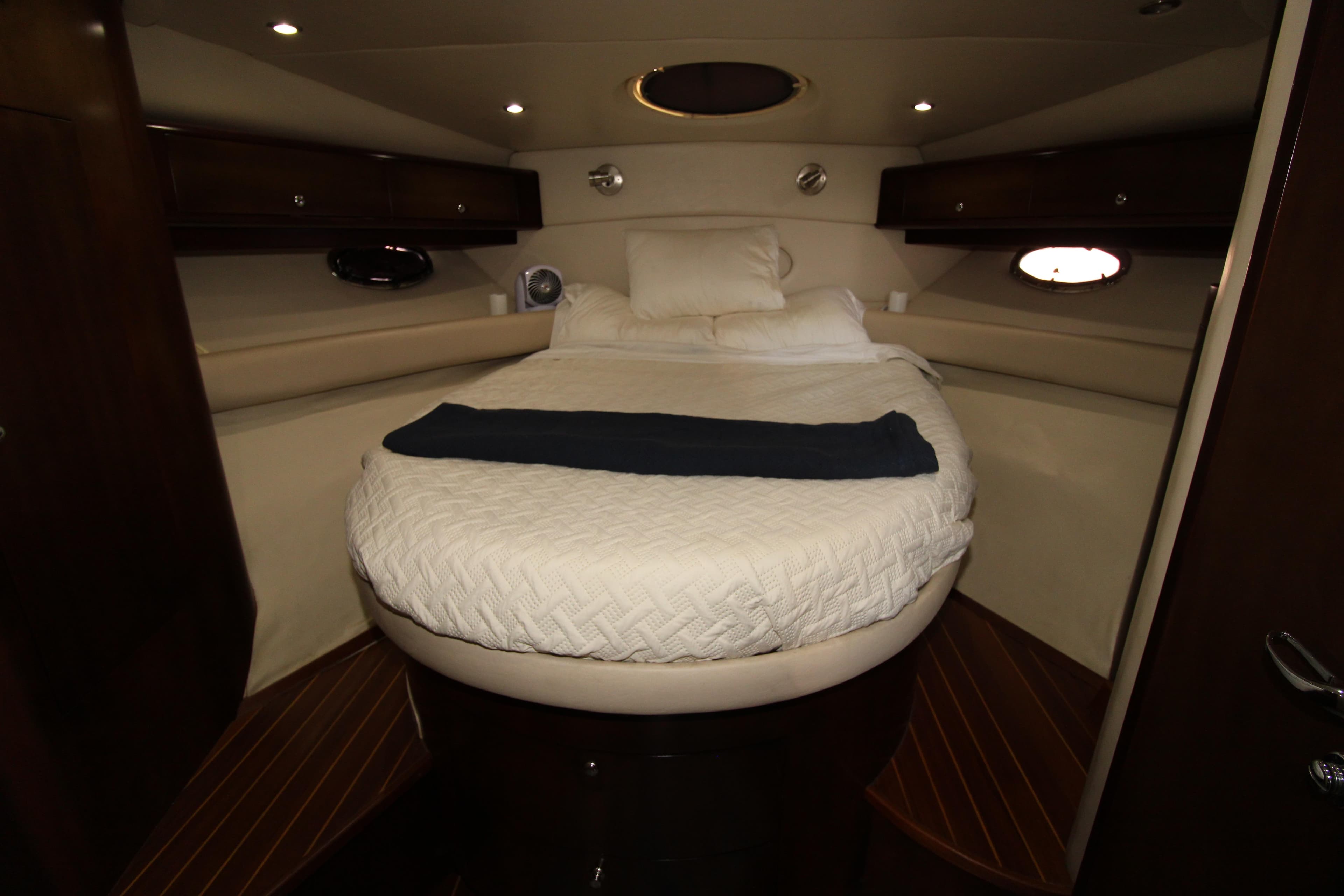 Luxurious cabin interior of 2002 Regal Commodore 4260 yacht with cozy bed and ambient lighting.