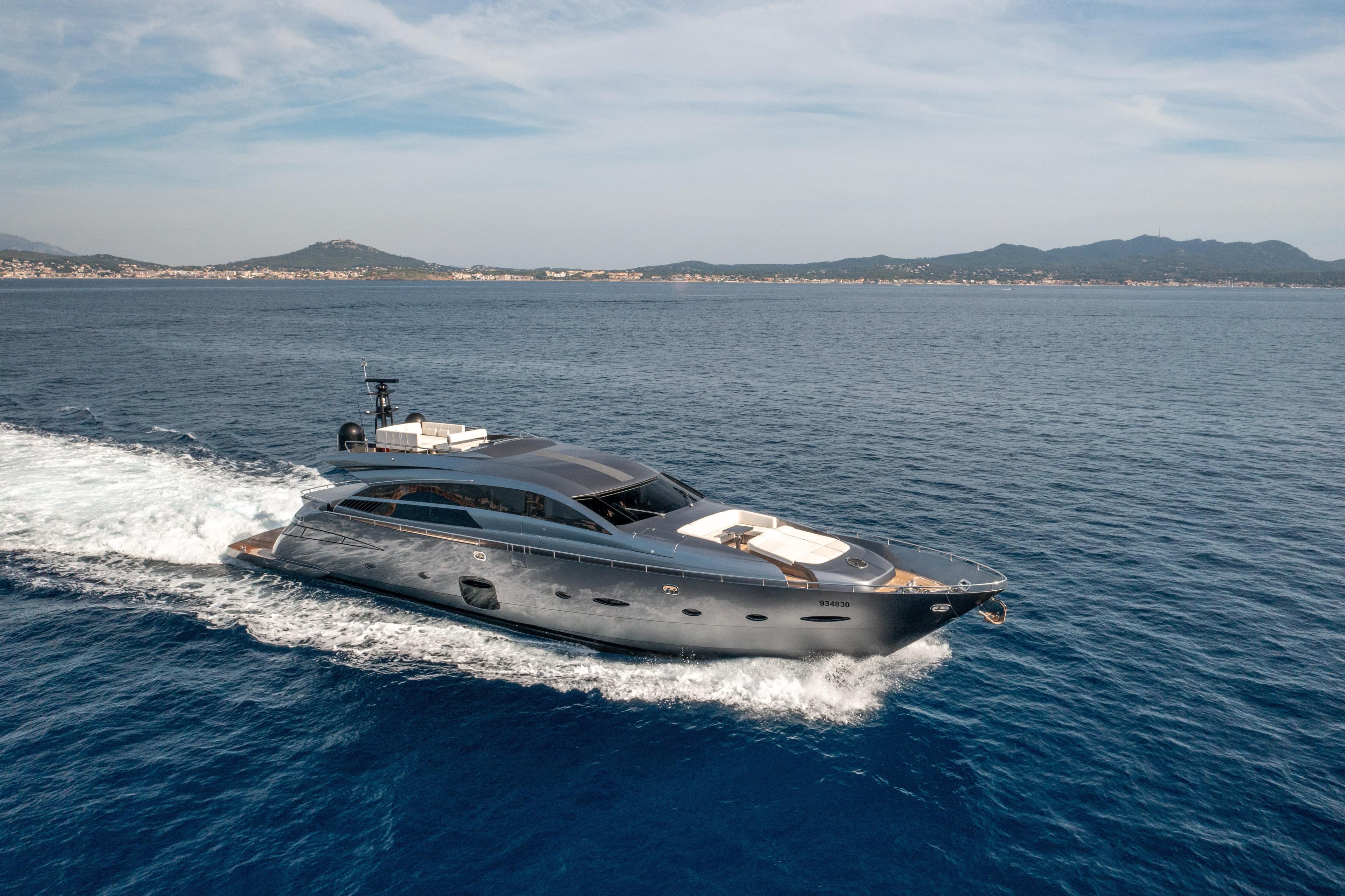 Luxurious 2012 Pershing 92 yacht cruising on open sea with scenic coastline backdrop.
