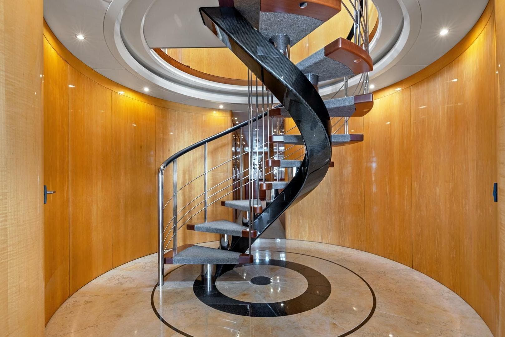 Luxurious spiral staircase inside 2005 New Zealand Yachts 115 Wave Piercer, featuring elegant wood paneling.