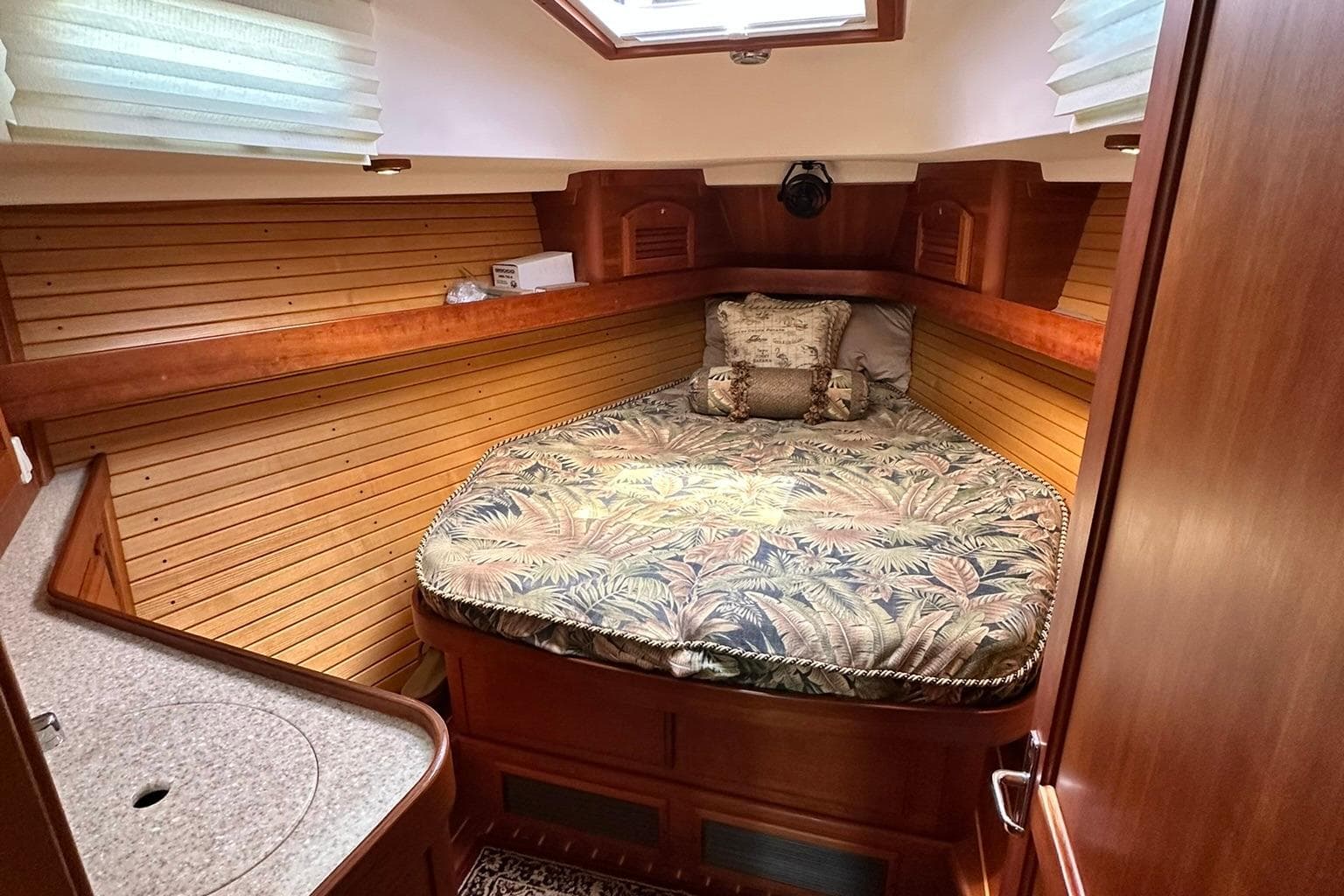 Cozy cabin interior of 2007 Sabre 386 yacht with patterned bedding and wooden paneling.