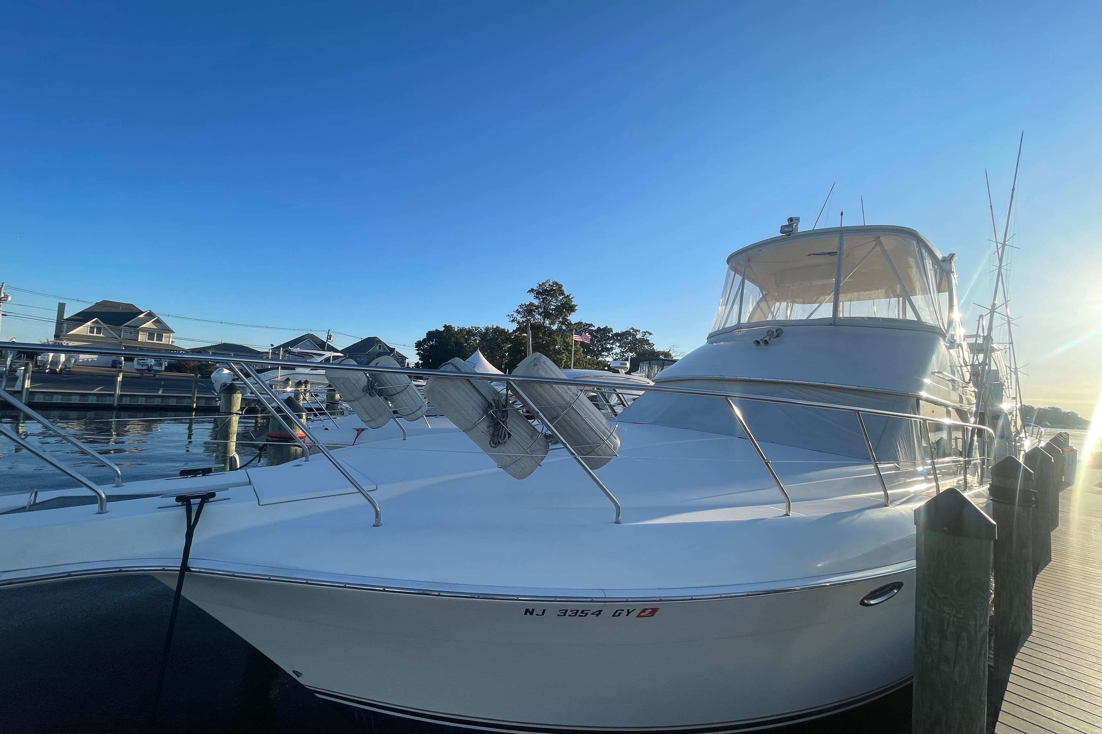2006 Silverton 42 Convertible yacht docked at marina under clear blue sky.