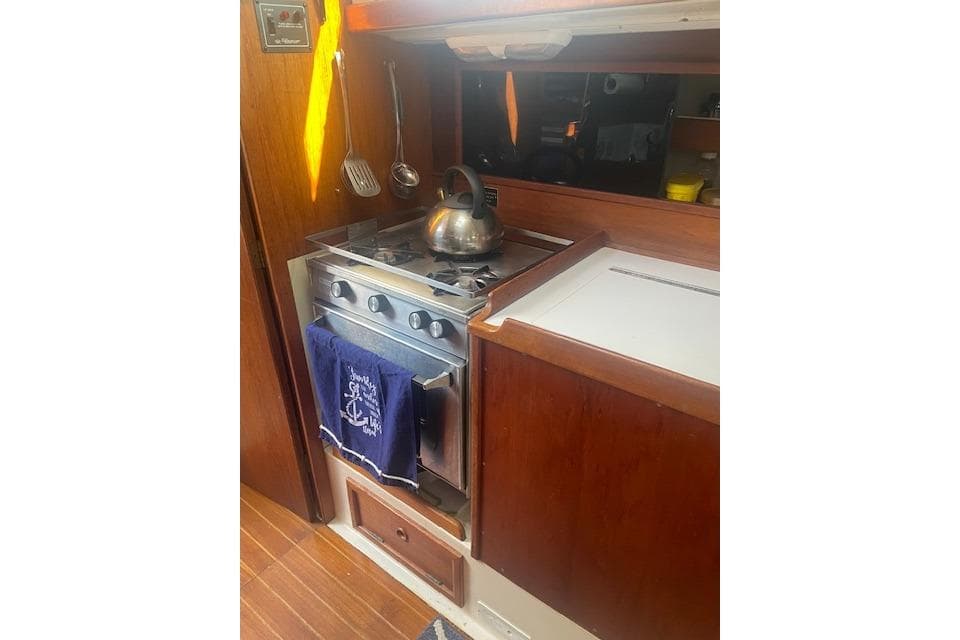 1978 Hinterhoeller Niagara 35 Classic yacht kitchen with stove, kettle, and hanging utensils.