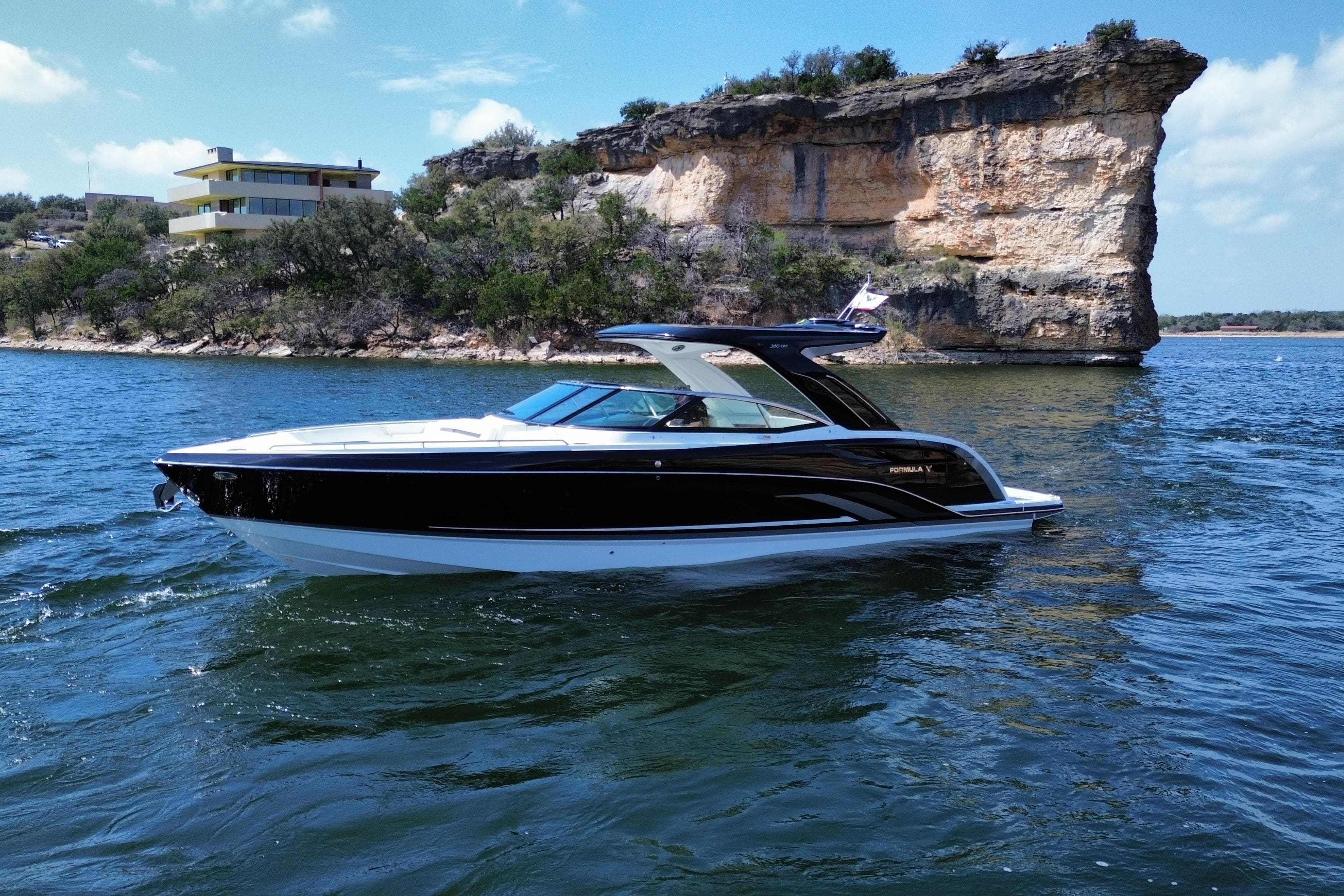 2026 Formula 360 Crossover Bowrider I/O cruising on a scenic lake with rocky cliffs.