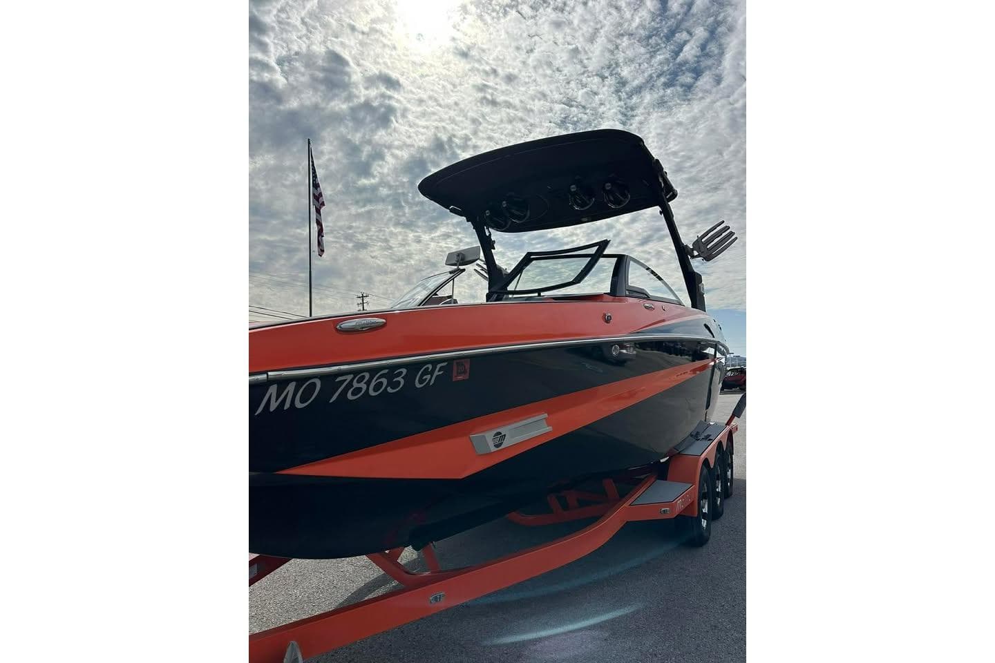 2017 Malibu M235 boat with orange and black design under cloudy sky.