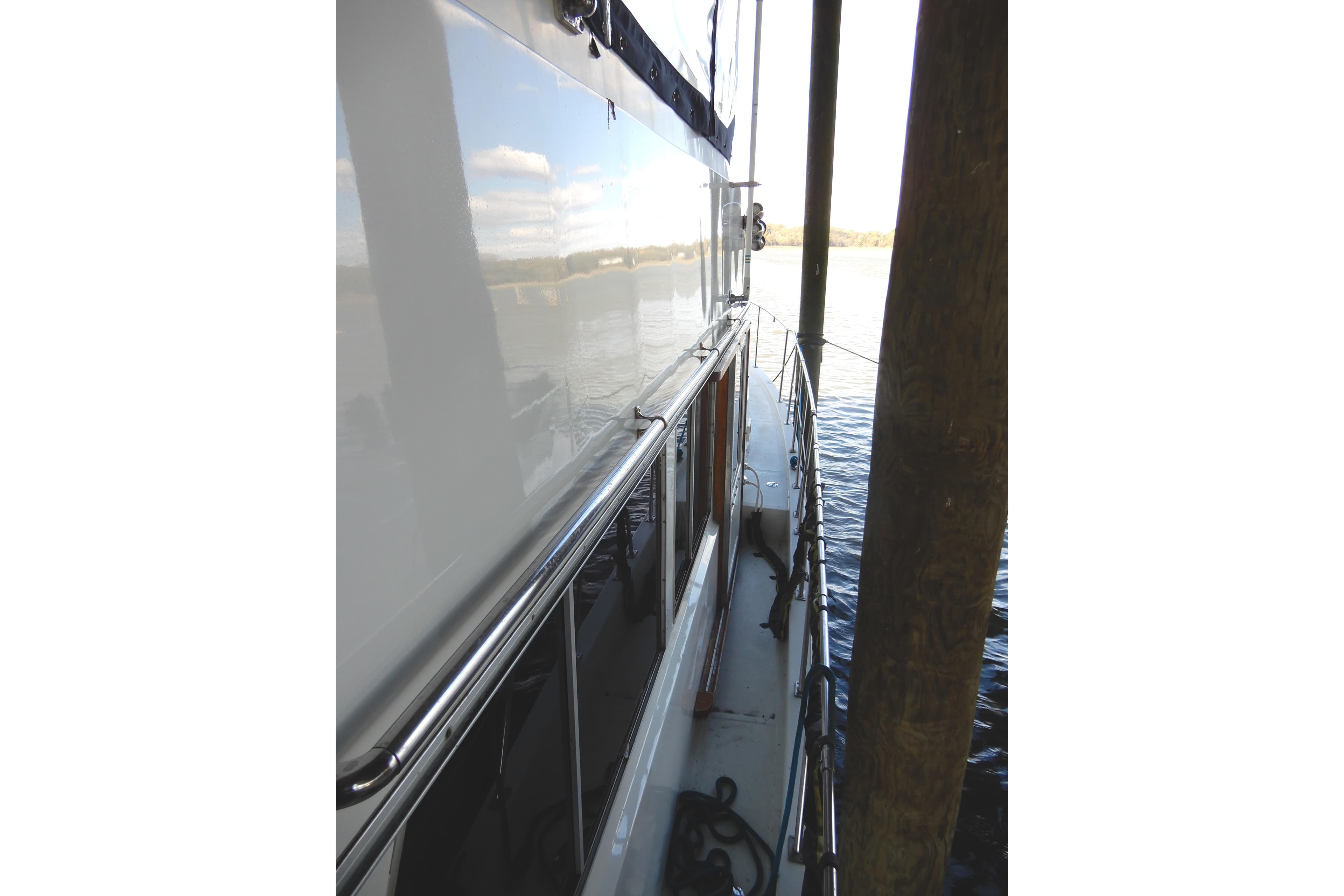 1989 Jefferson 46 Sundeck yacht docked, side view with railing and water reflection.
