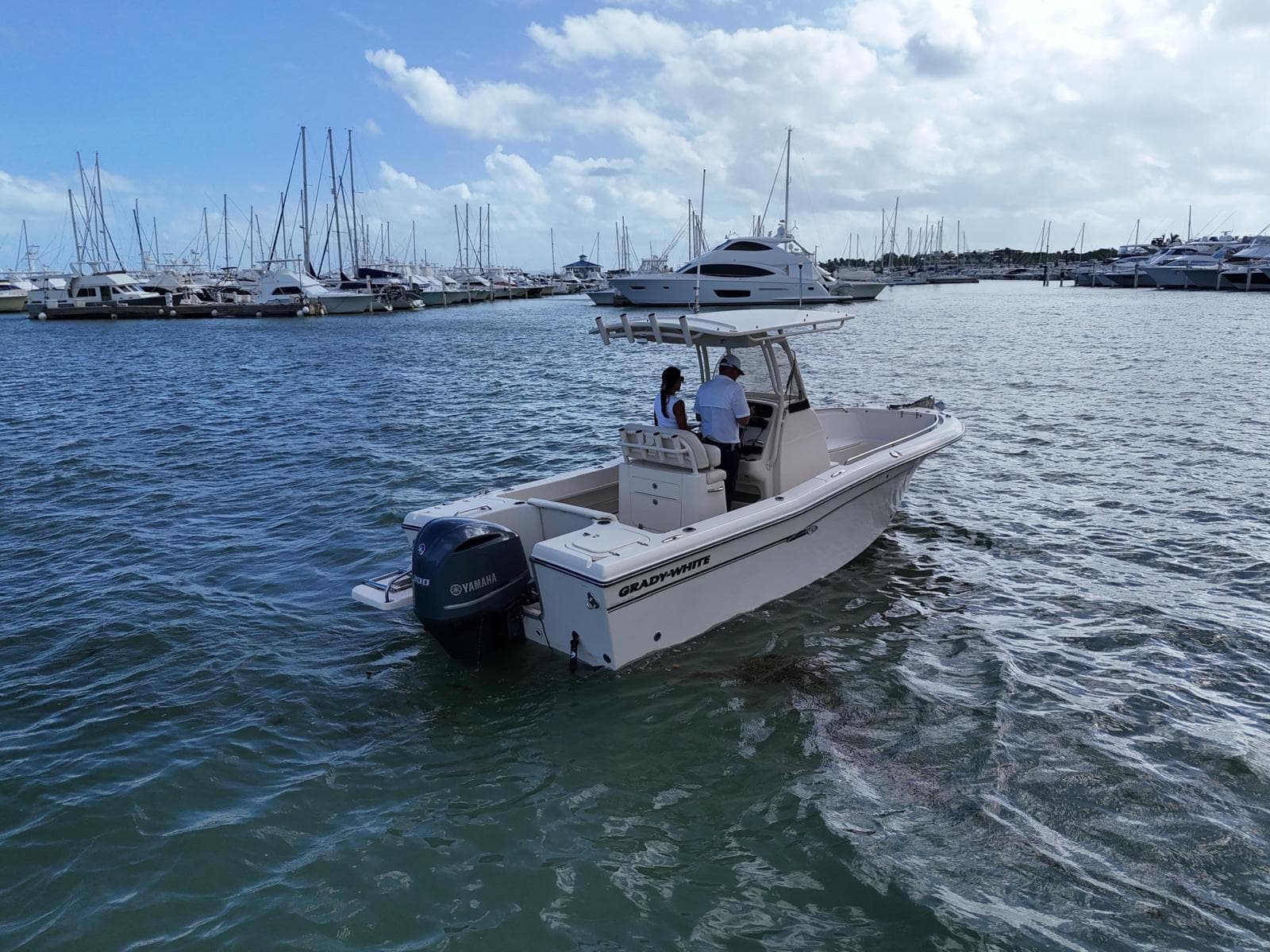 2016 Grady-White Fisherman 230 boat cruising in a marina with sailboats.