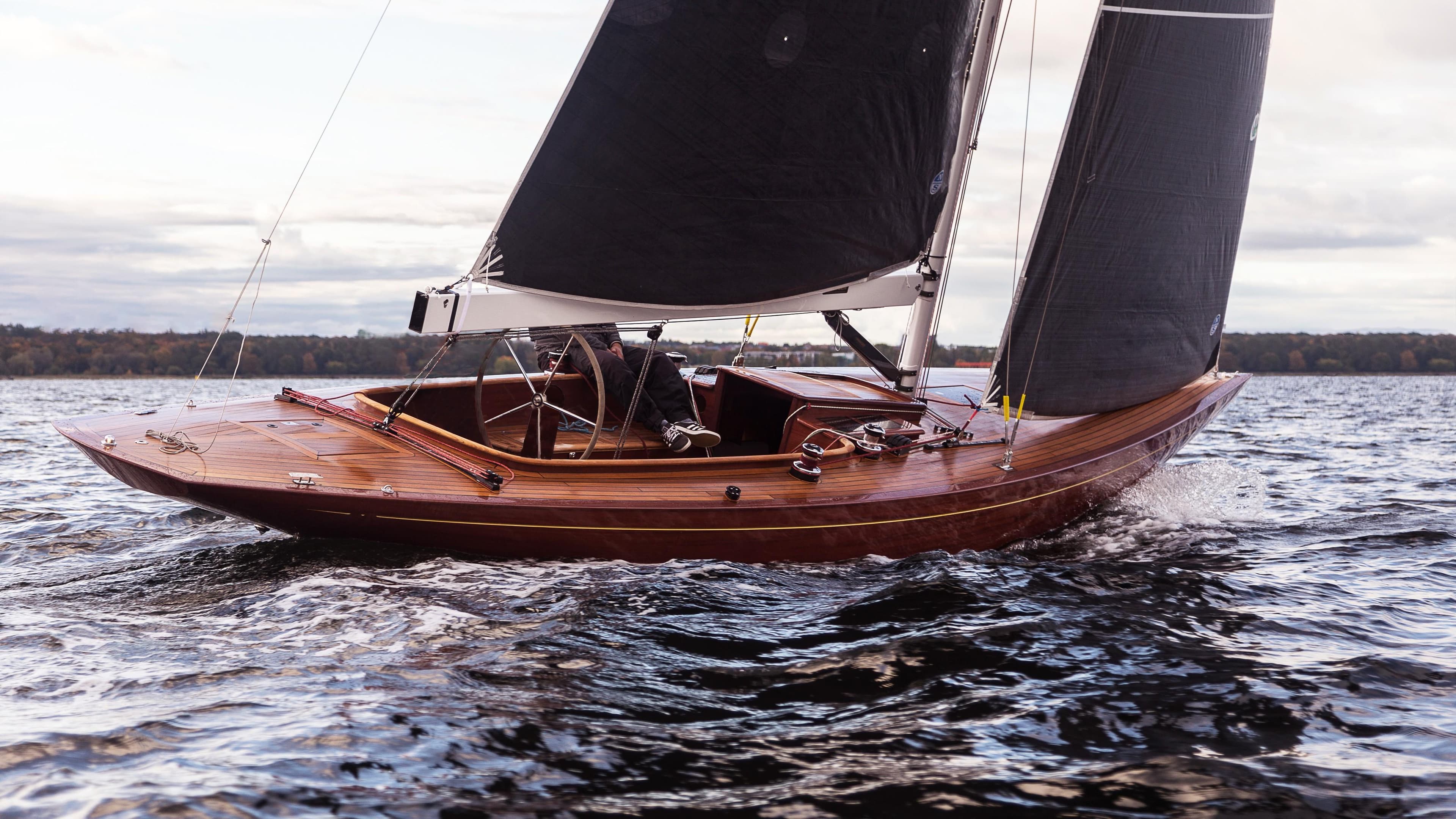 Sleek 2017 Hoek Classic 33 sailboat gliding on water with dark sails.