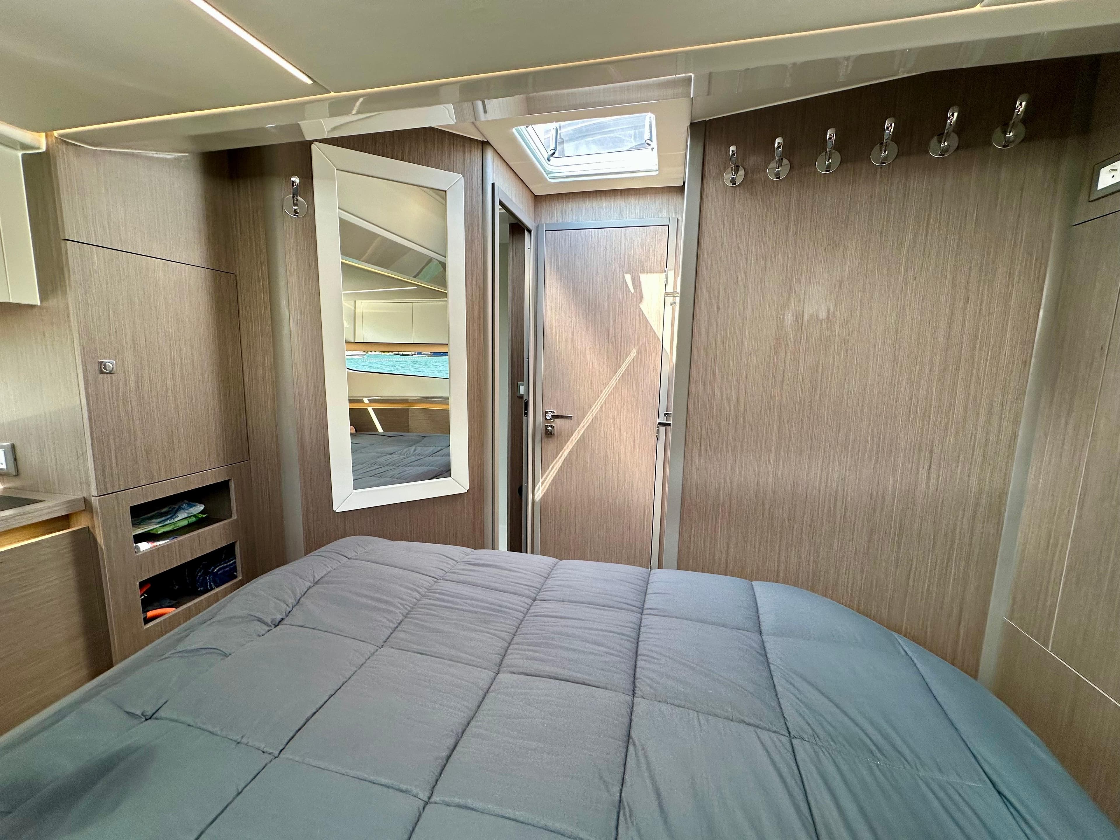 2024 Jeanneau Merry Fisher 1295 Flybridge cabin interior with bed, mirror, and wooden finish.