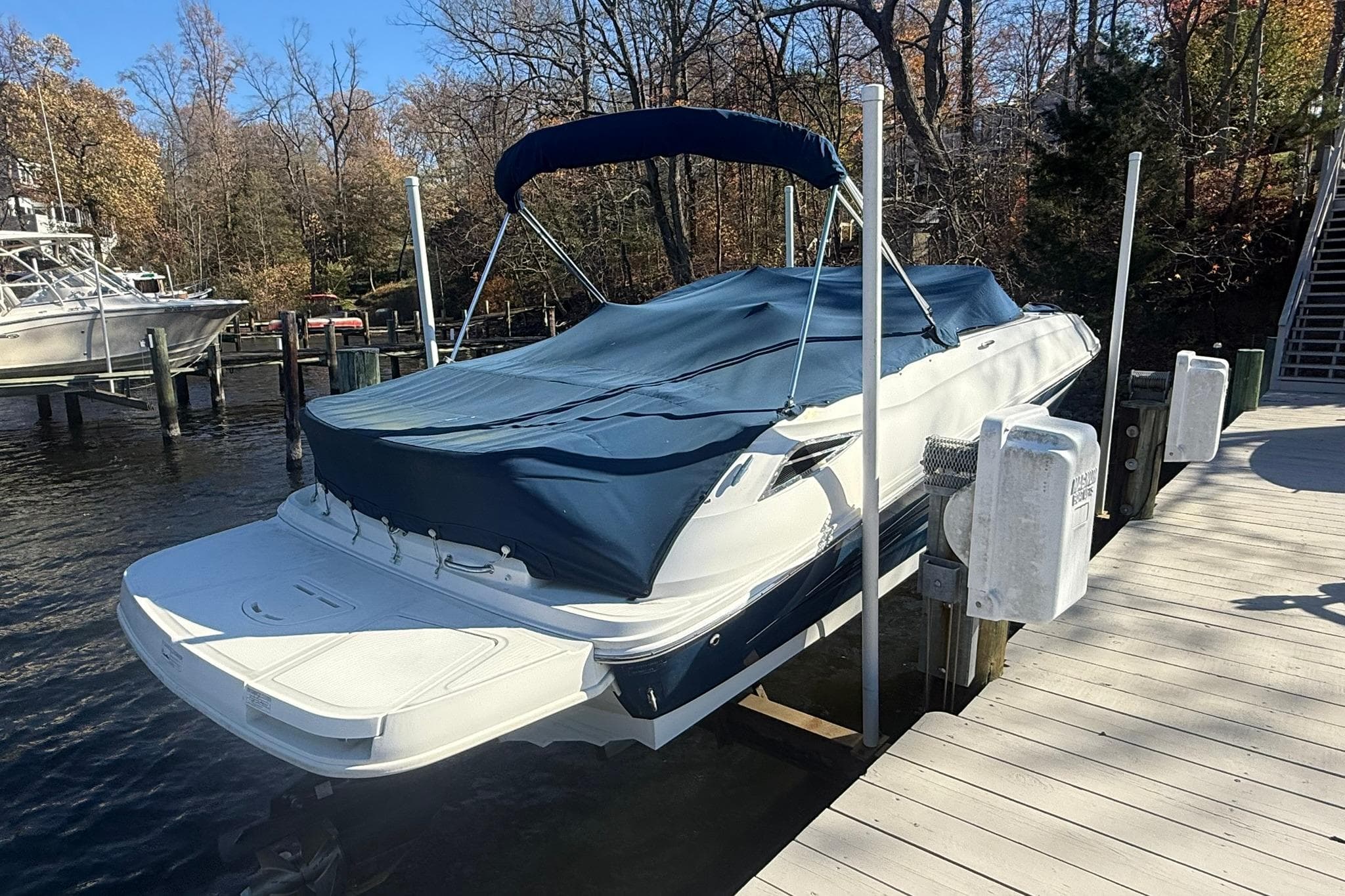 2015 Sea Ray 240 Sundeck boat docked with cover, surrounded by autumn trees.