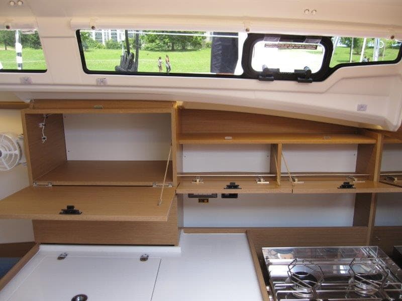Interior of 2025 Jeanneau Sun Odyssey 350 yacht with open wooden cabinets and stove.