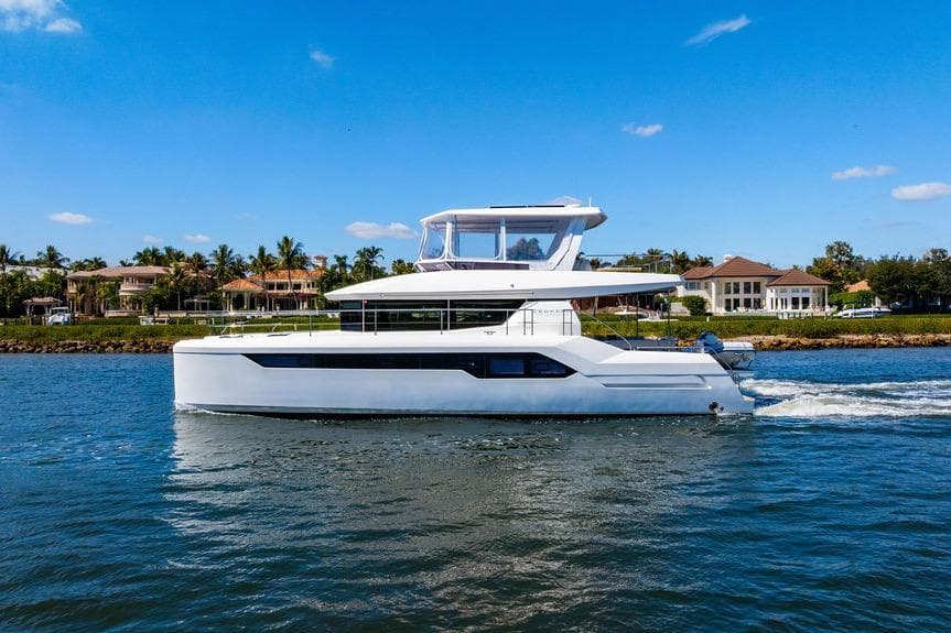 2022 Leopard 53 Powercat cruising on a sunny day near waterfront homes.