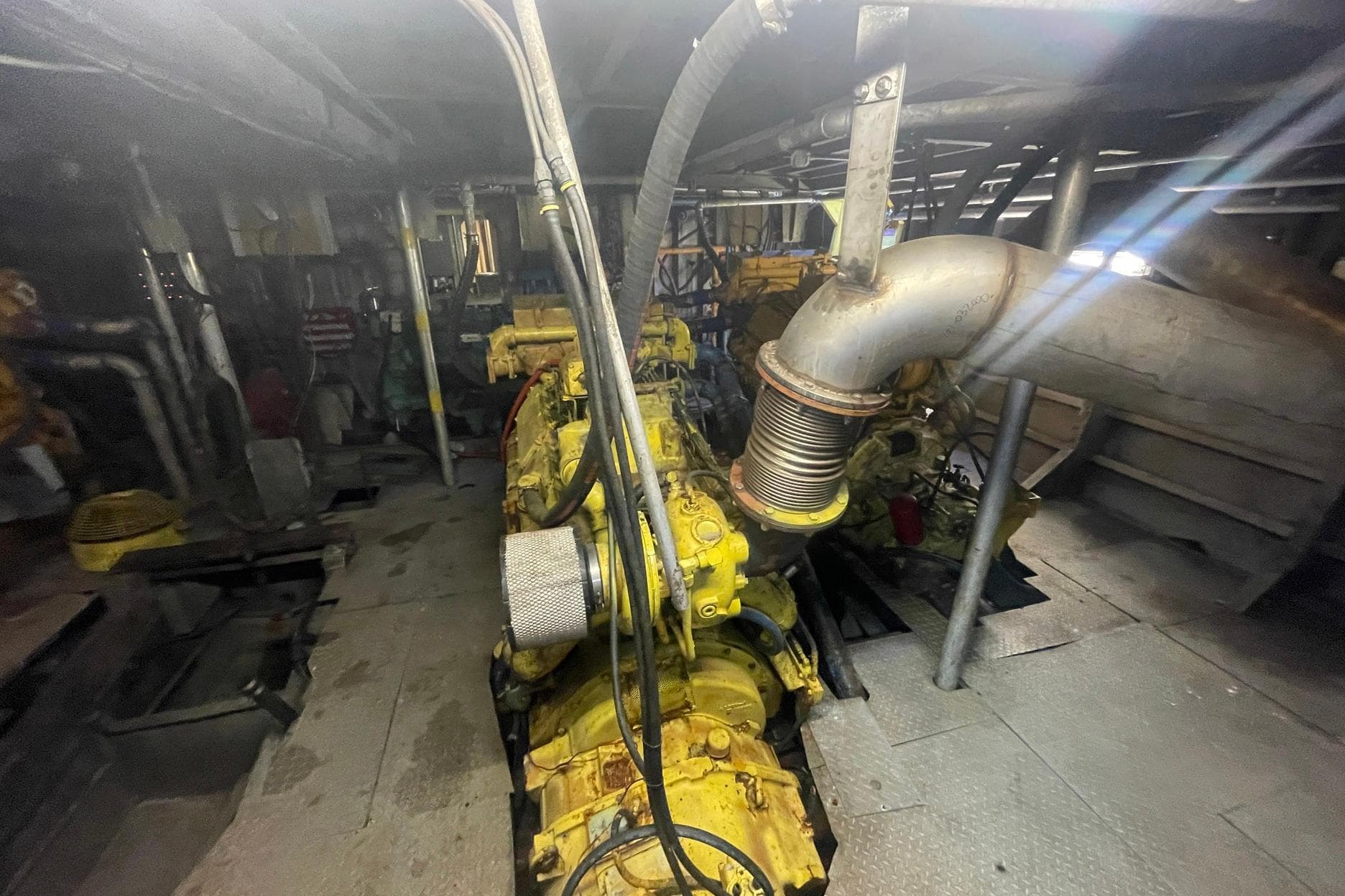 Engine room of a 1993 Breaux Brothers Crew Boat, featuring yellow machinery and piping.