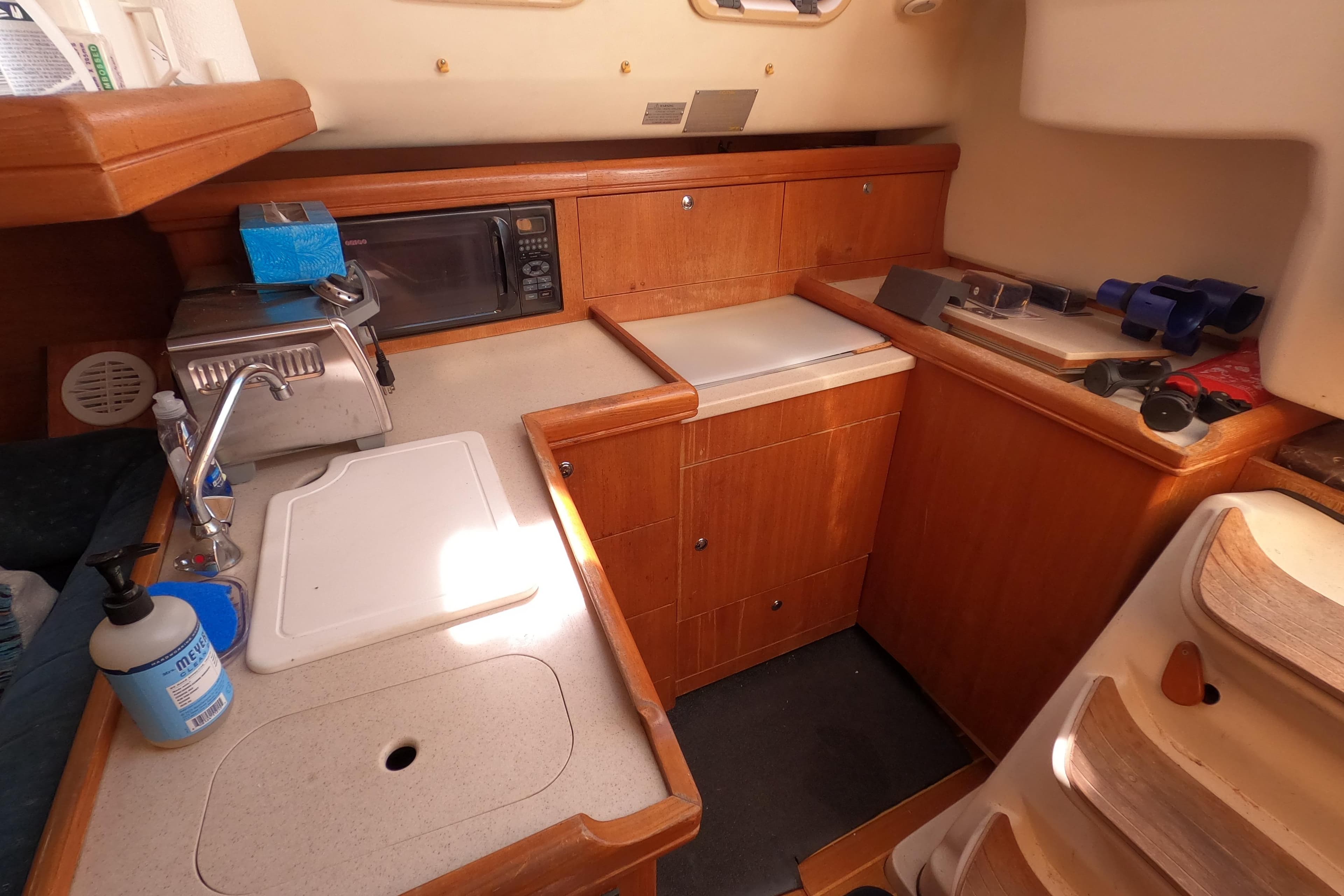 2003 Hunter 326 yacht interior kitchen with wooden cabinetry and appliances.