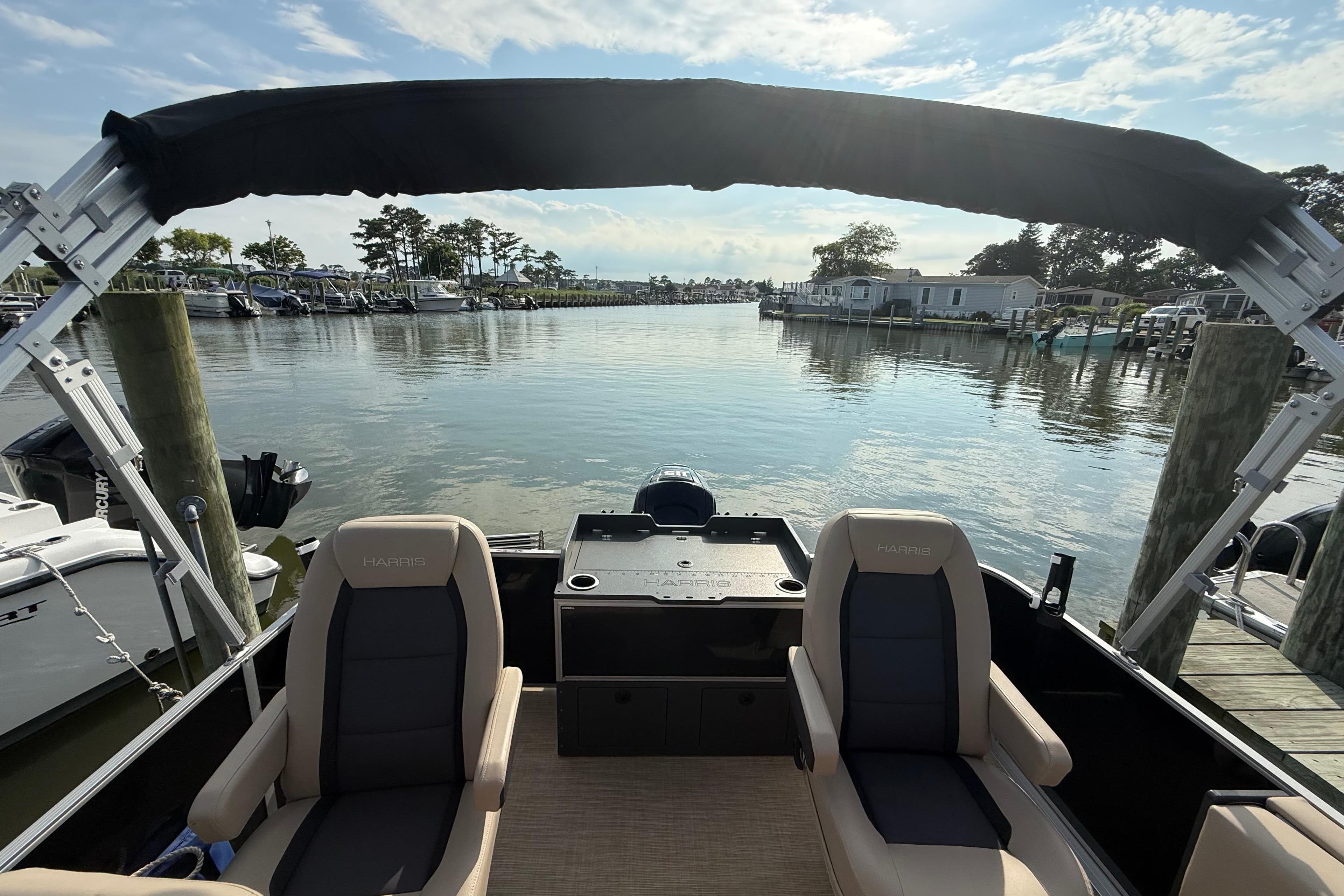 2025 Harris Cruiser 230 pontoon boat docked, featuring comfortable seating and scenic waterfront view.