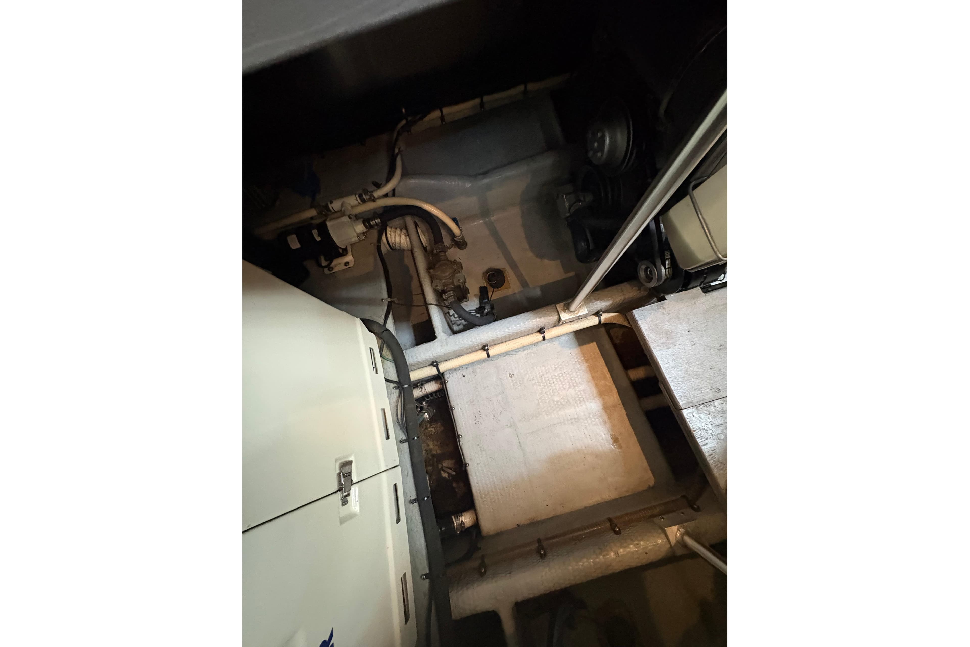 Engine room of a 1997 Mainship 34 Motor Yacht, showcasing mechanical components and piping.
