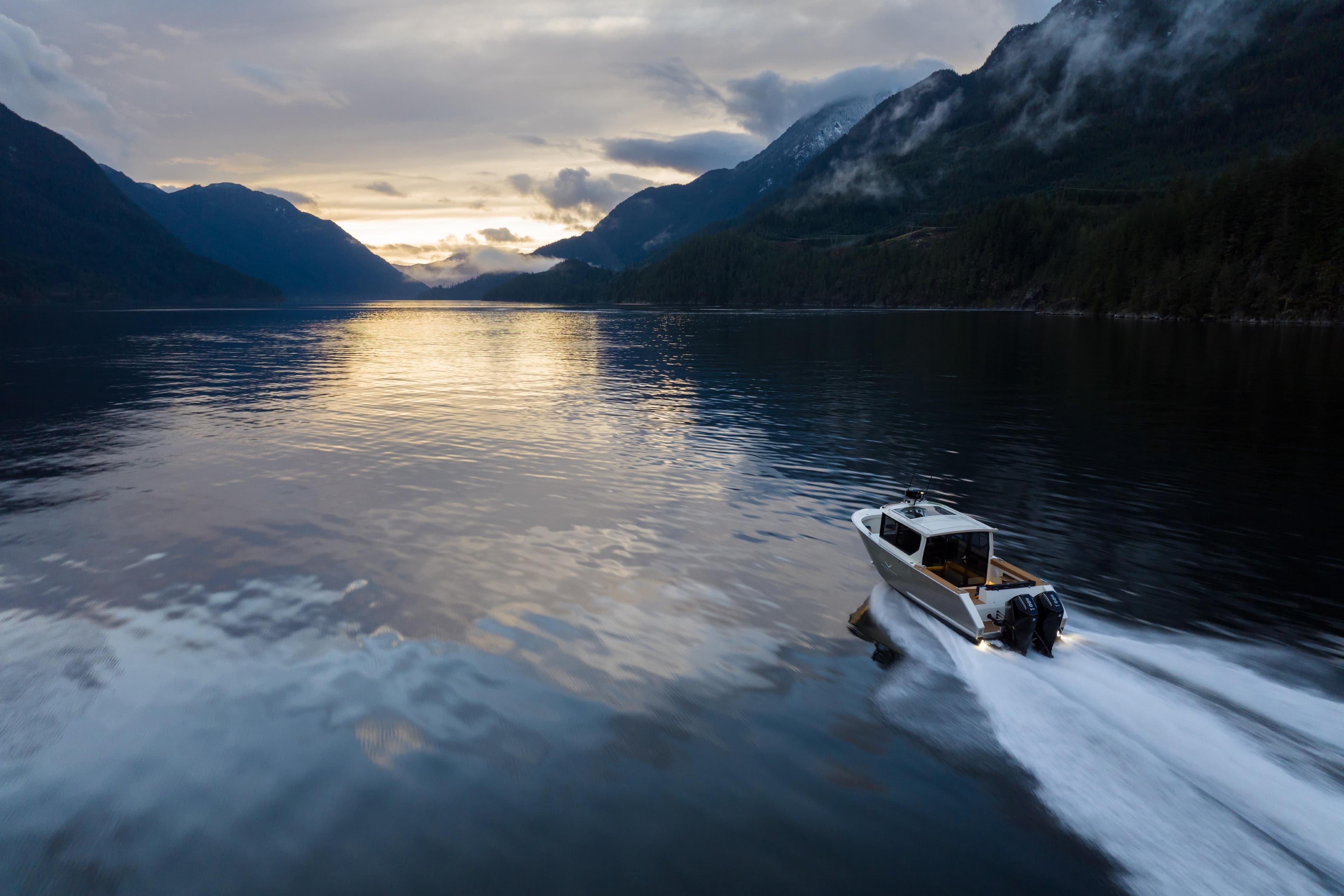 Jasper Marine Defender 22 cruising on a serene lake at sunset, surrounded by mountains.