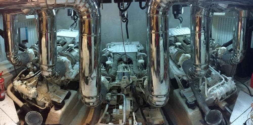 Engine room of 2000 Astondoa 82 GLX yacht with polished metal pipes and machinery.