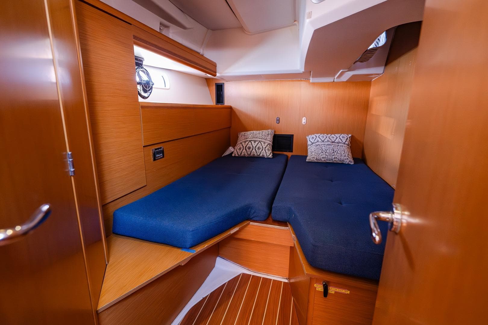 Cozy cabin interior of 2010 Jeanneau 53 yacht with twin beds and wooden finish.