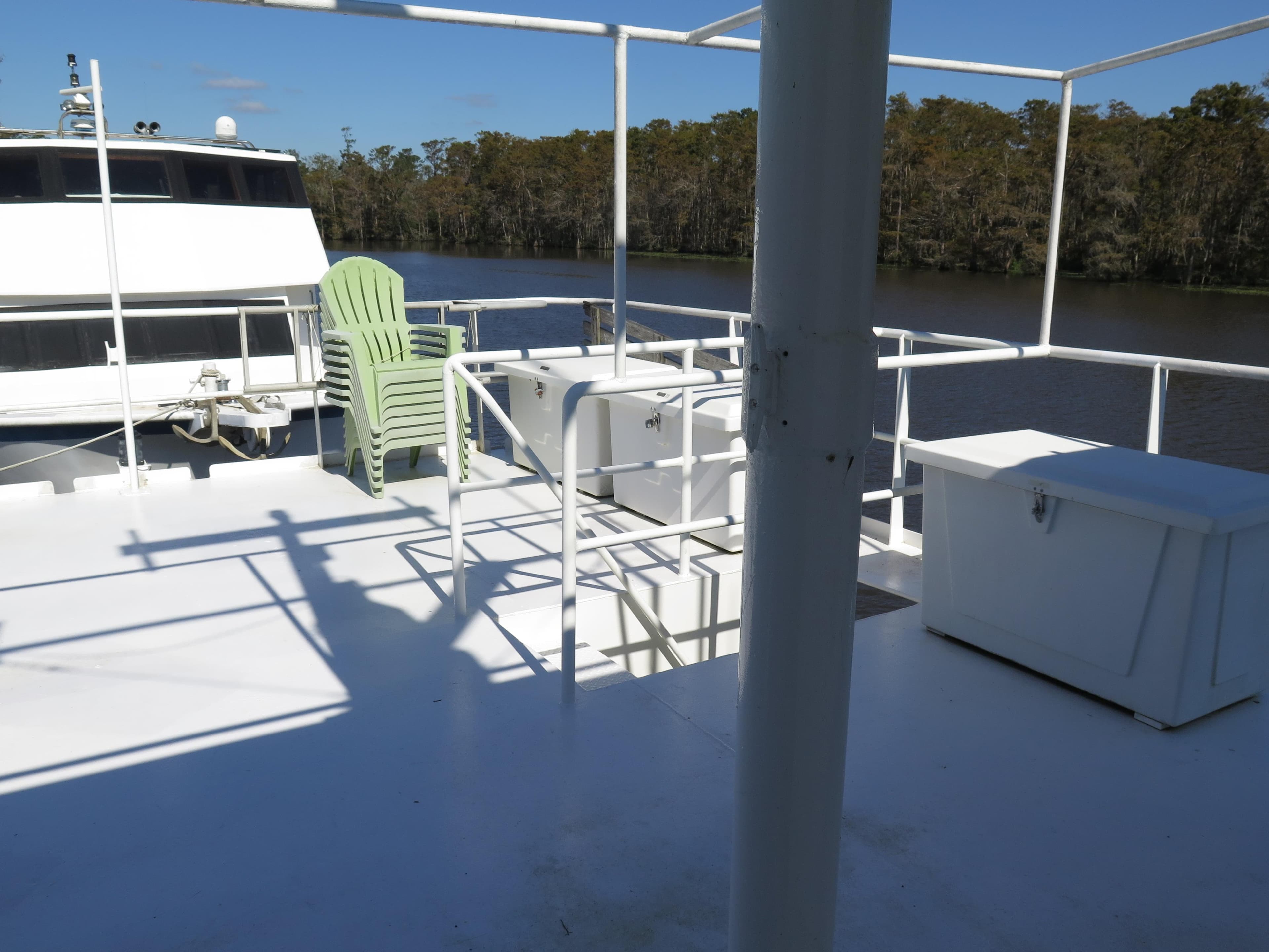 Upper deck of a 1998 Rodriquez Custom boat with green chair and storage boxes.