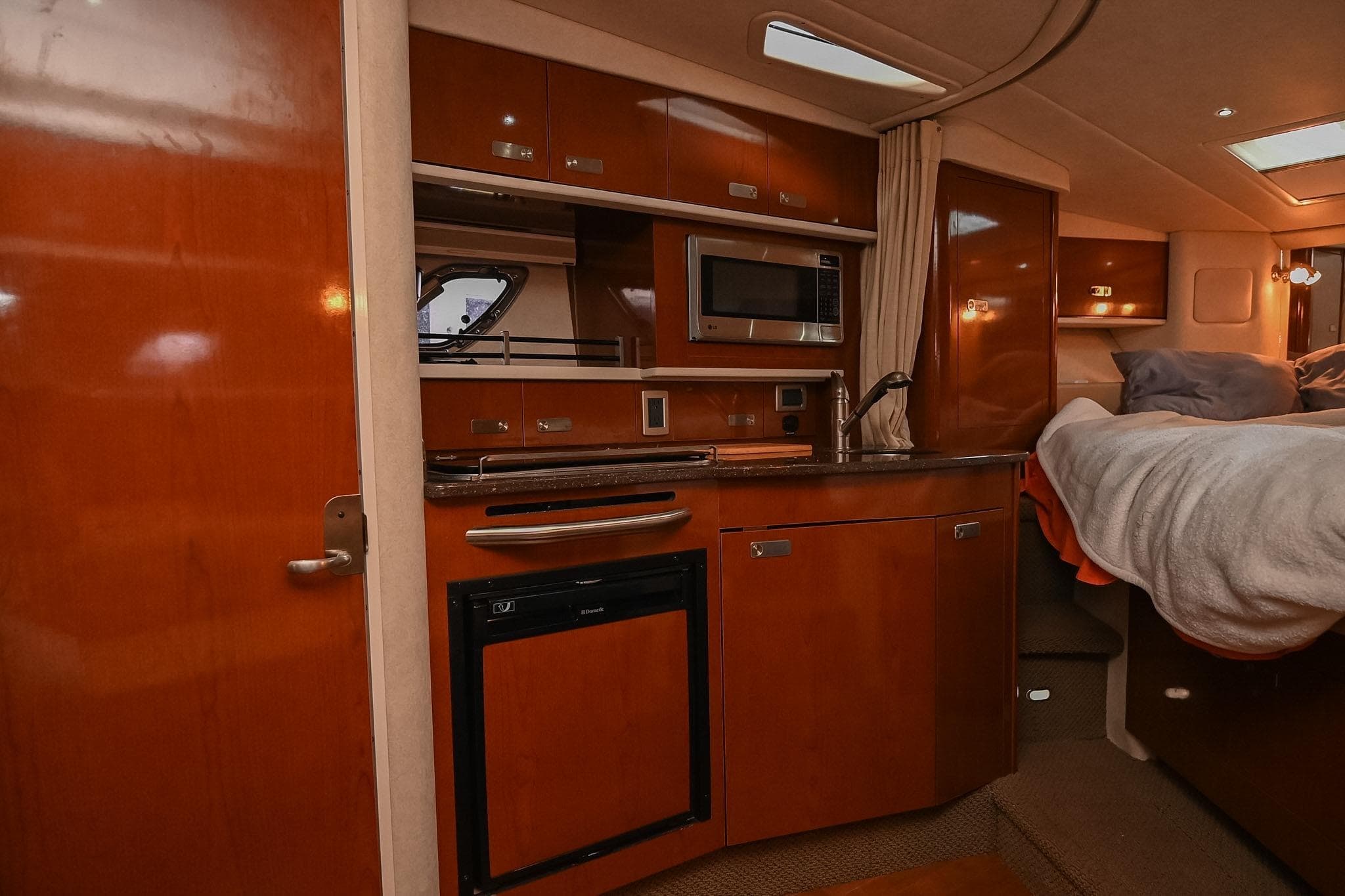 2012 Sea Ray Sundancer 330 interior with kitchenette, microwave, and cozy sleeping area.