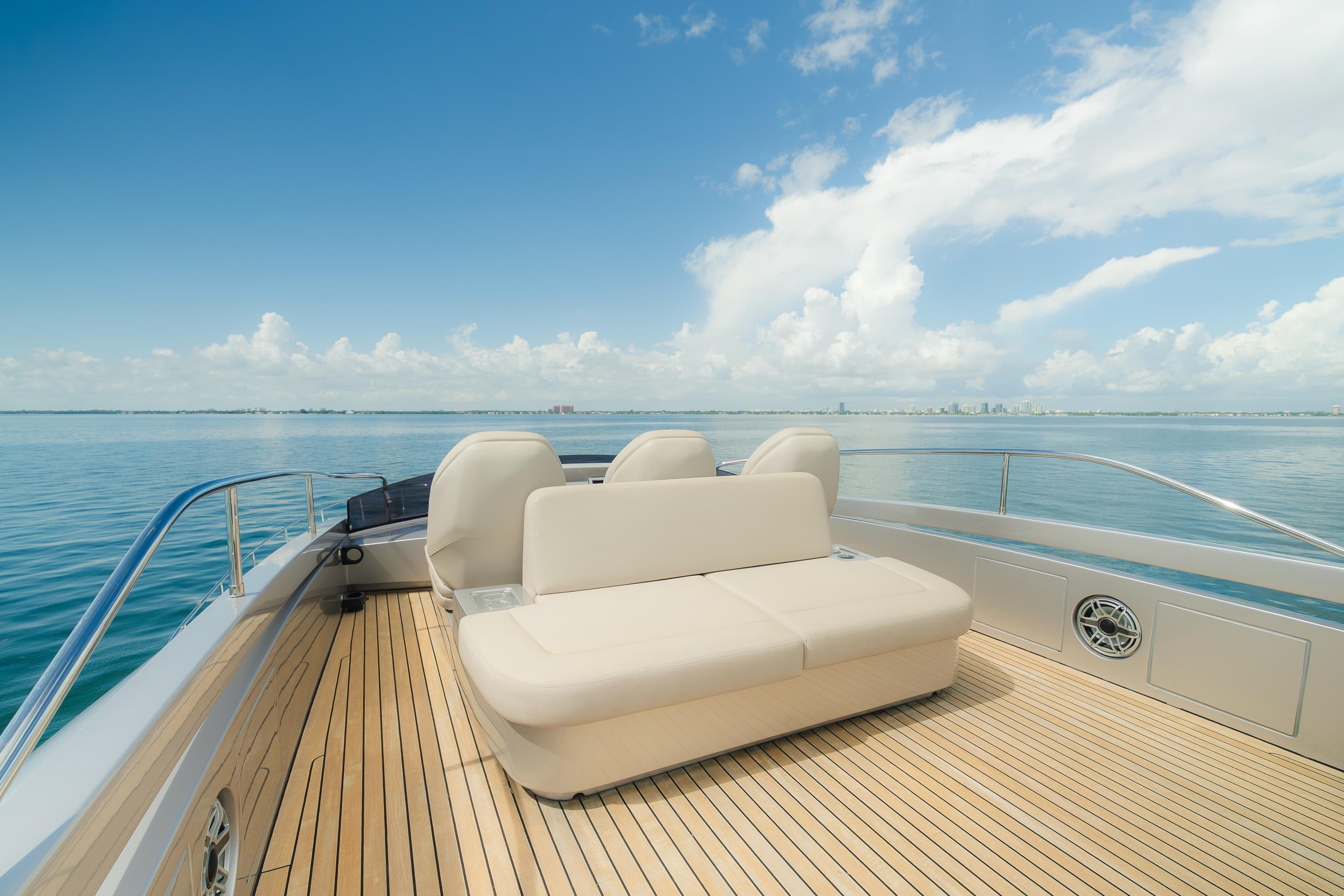Luxurious 2021 Pershing 8X yacht deck with seating, overlooking calm ocean and clear sky.