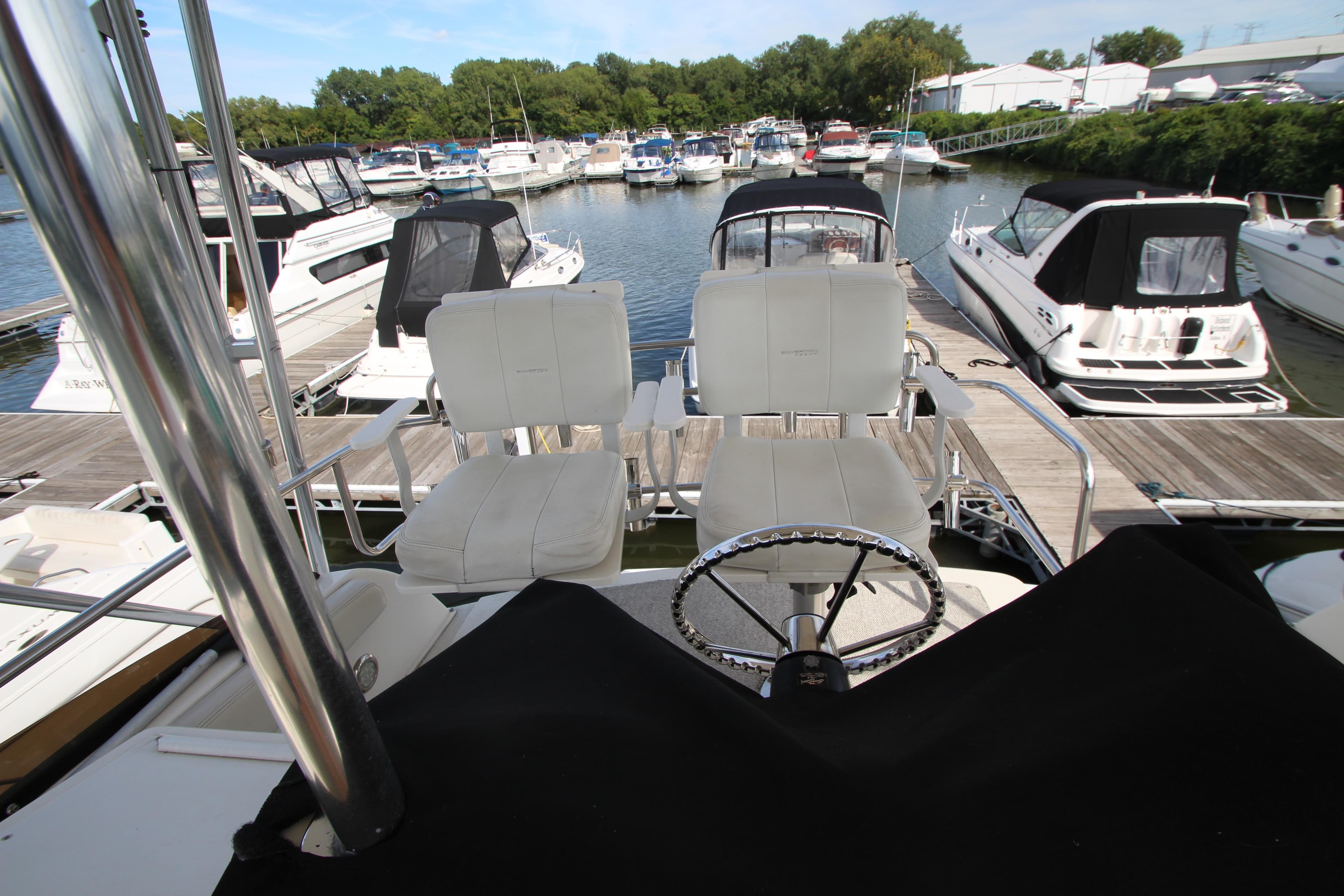 2000 Silverton 37 Convertible yacht at marina, featuring helm and seating area.