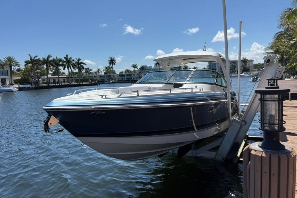 2025 Formula 330 Crossover Bowrider OB docked by a scenic waterfront.