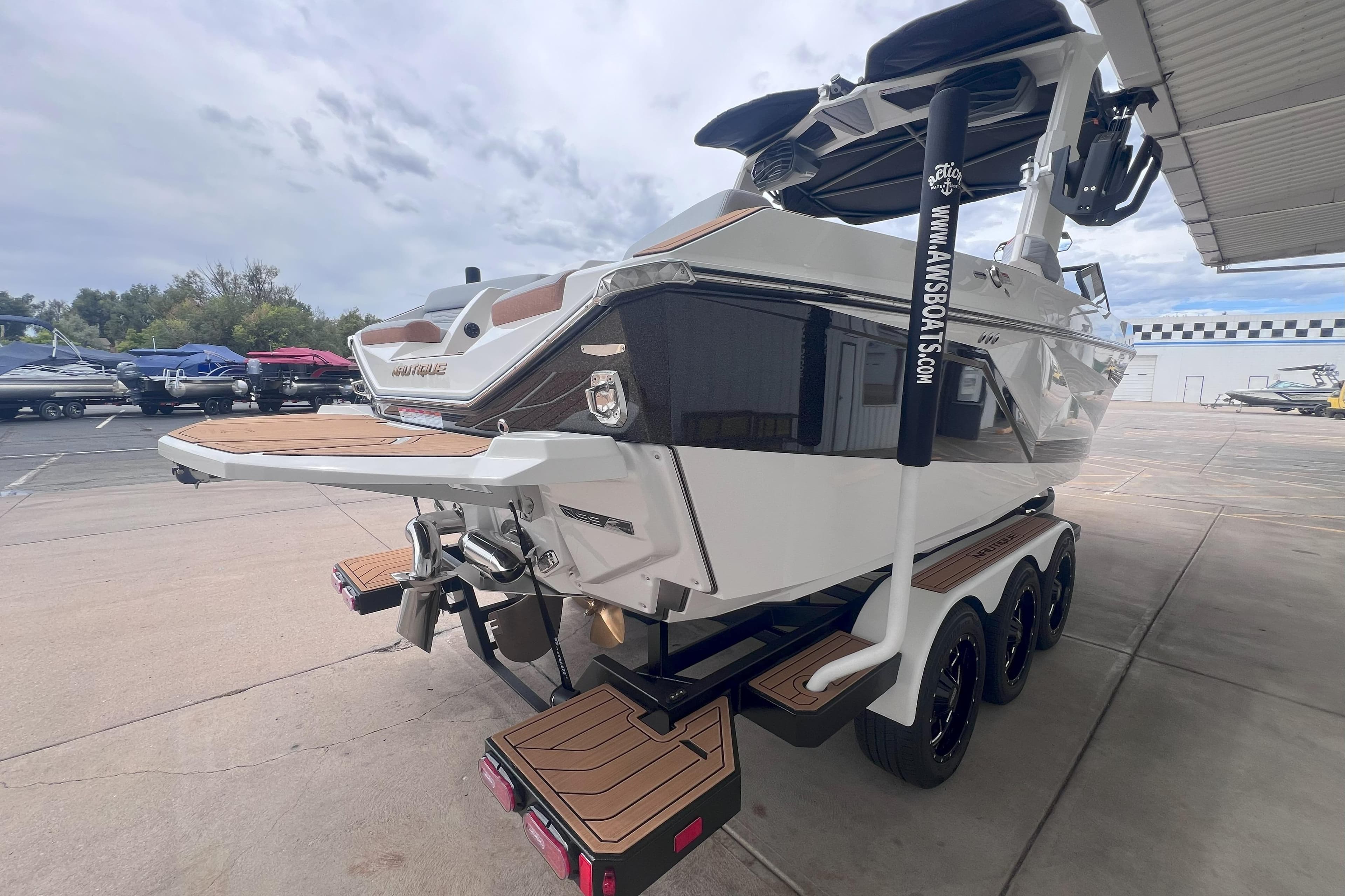 2025 Nautique Super Air Nautique G23 boat on trailer, rear view, in a marina setting.