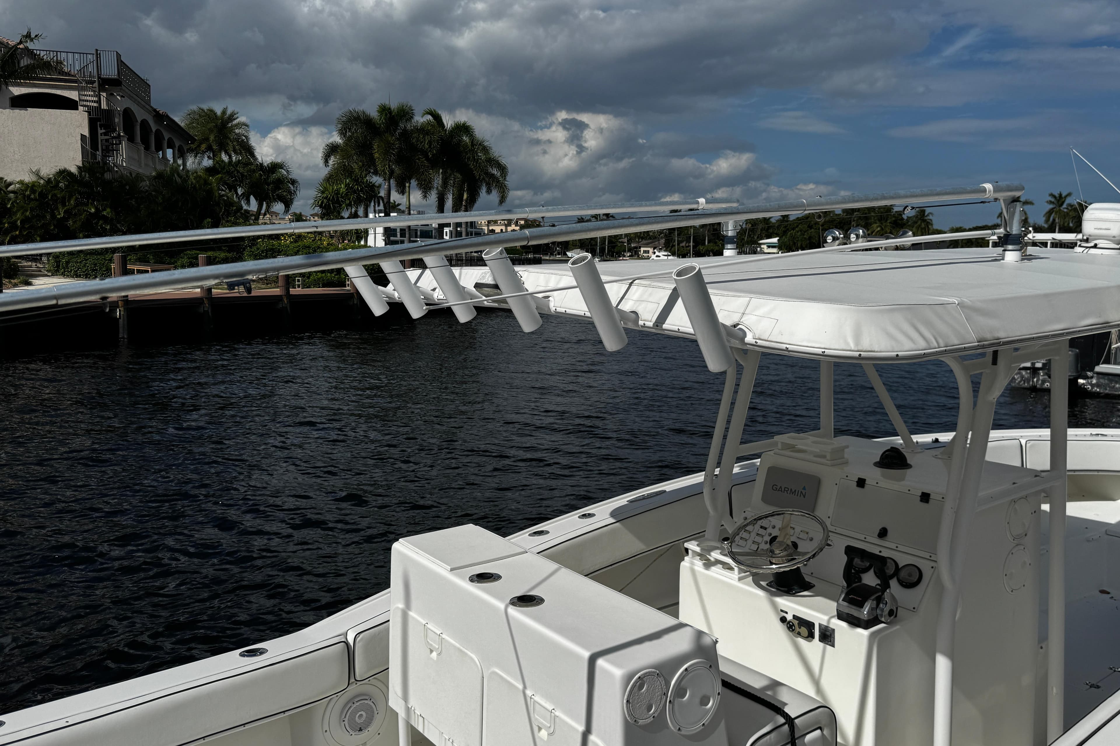 2004 Dusky 33 boat docked by waterfront with palm trees and cloudy sky.