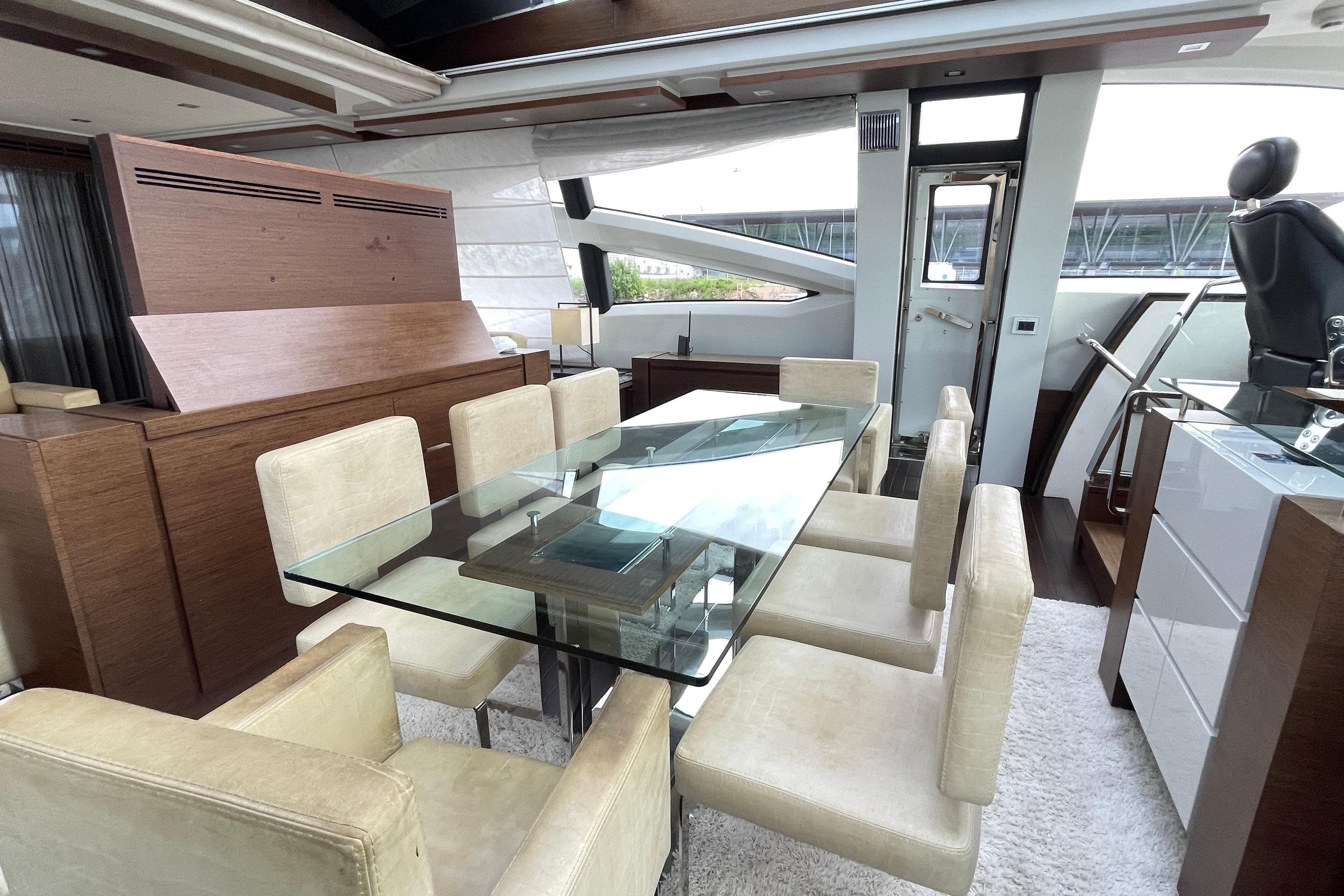 Luxurious interior of 2009 Azimut 103S yacht with glass dining table and beige chairs.