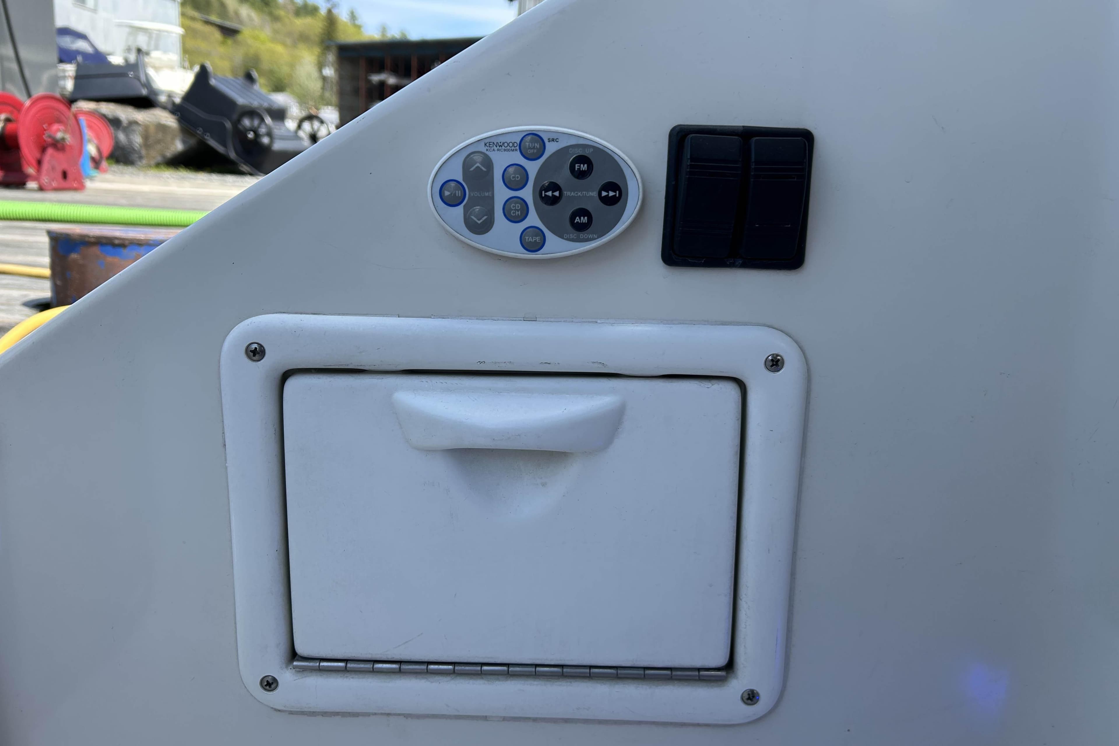 Control panel on a 2002 Regal Commodore 4260 boat with buttons and compartment.