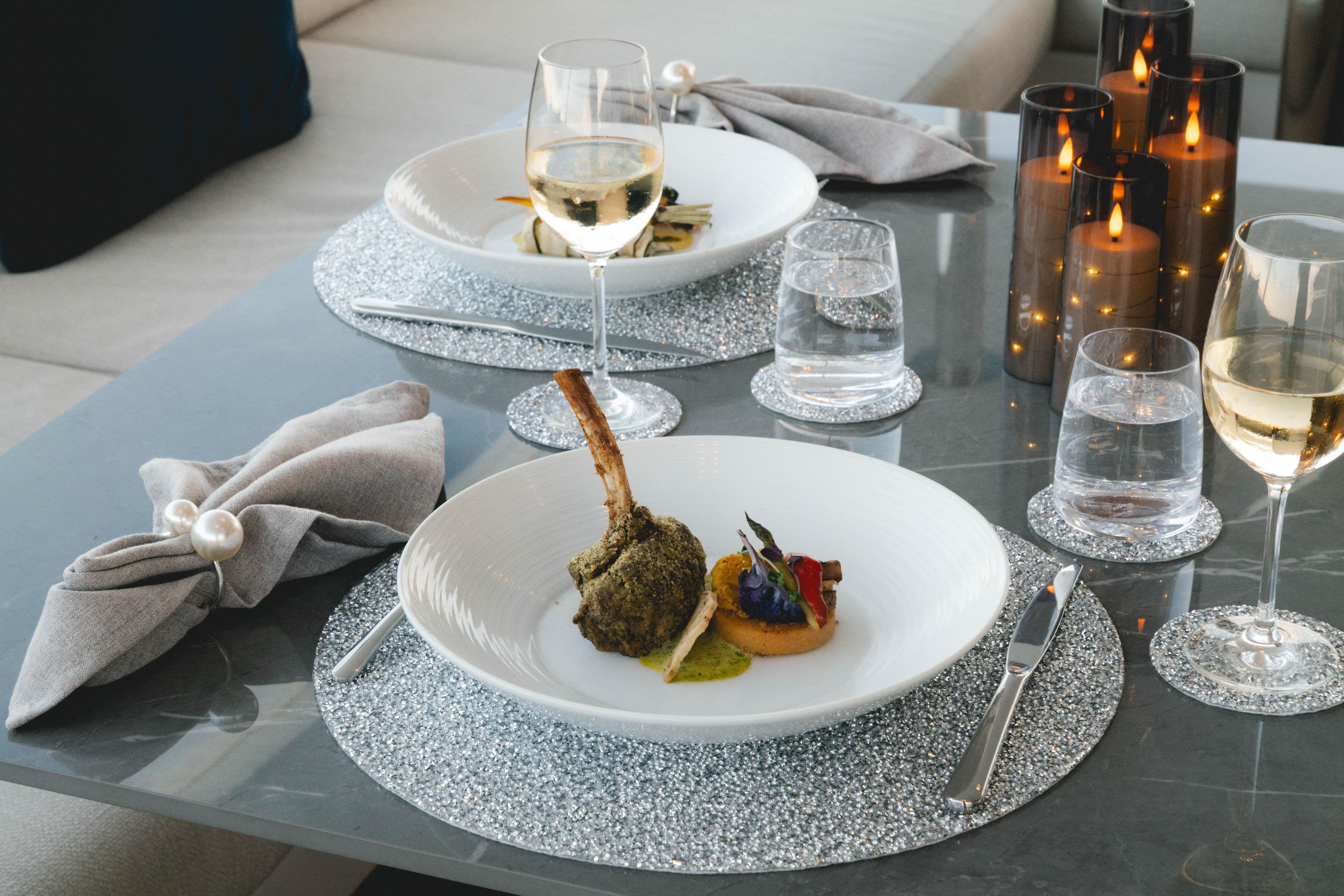 Elegant dining setup on Azimut yacht, featuring gourmet dish, wine, and candles, 2023.
