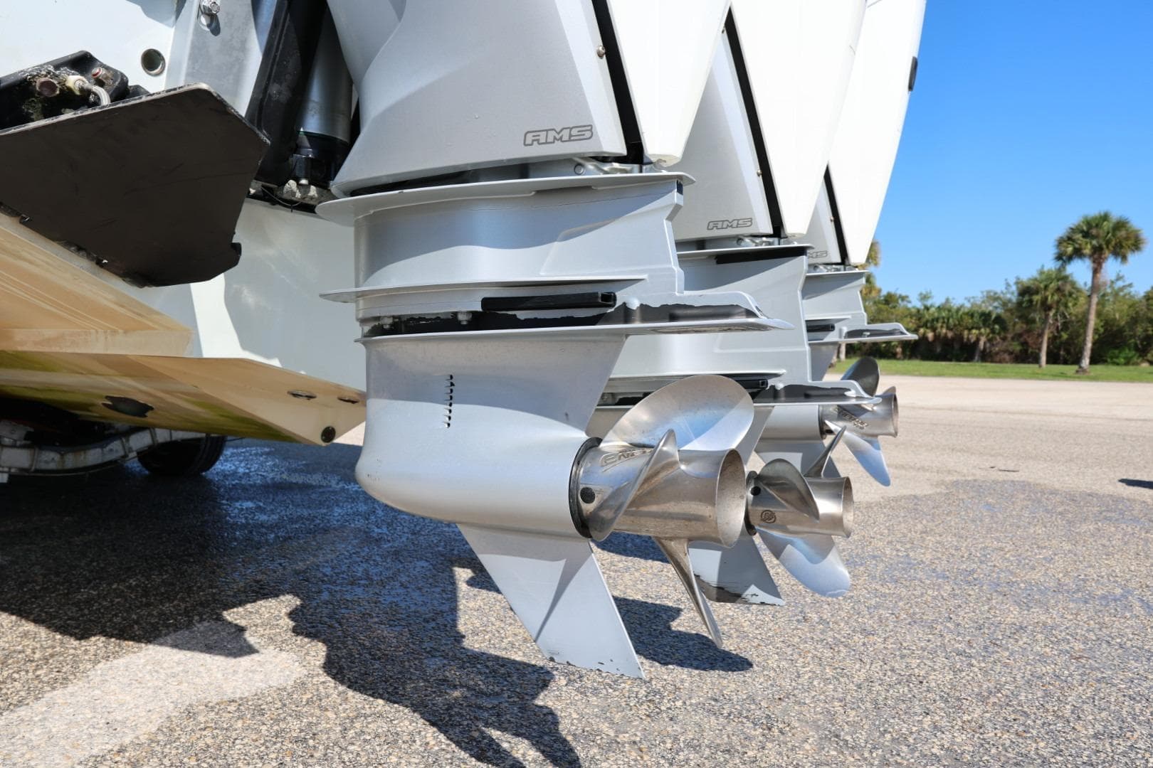 Triple outboard motors on a 2003 Contender 36 Open boat, parked on pavement.