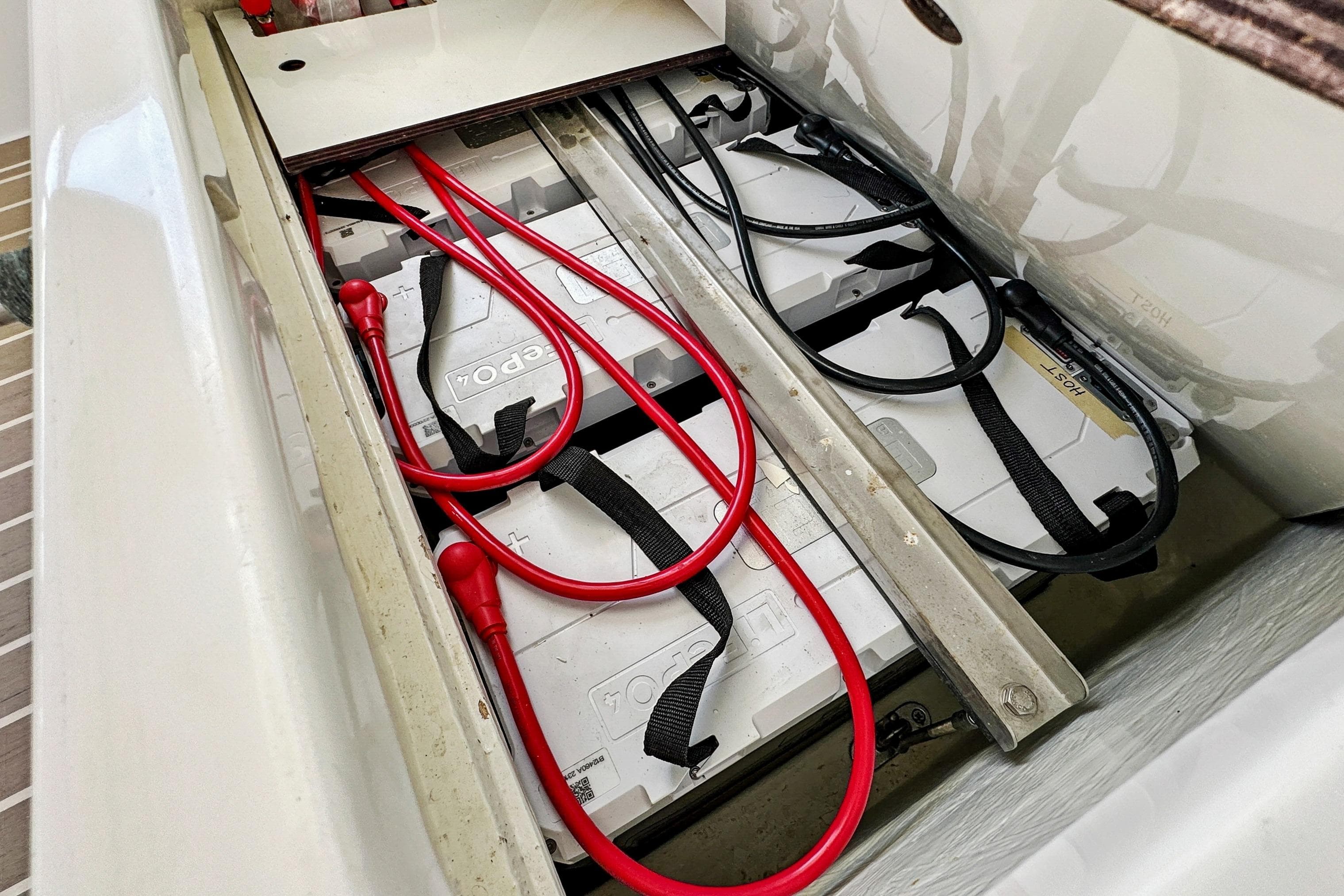 Battery compartment of a 2021 Leopard 45 yacht with red cables and secured batteries.