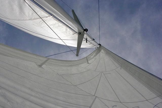 Sailboat with white sails against a clear sky, Hughes 40 model, 2012.
