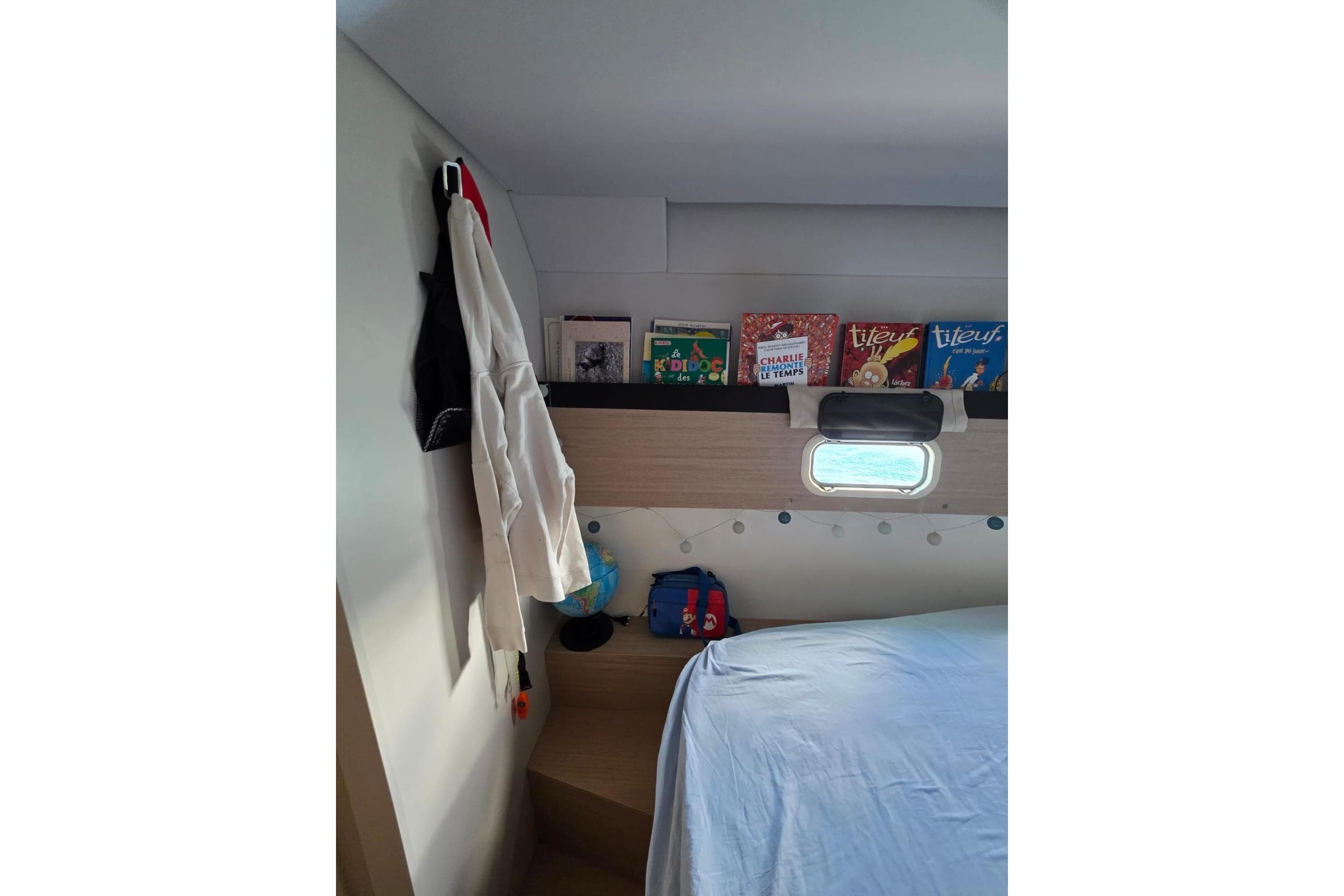 Cozy cabin interior of 2016 Bali 4.5 catamaran with books and window view.