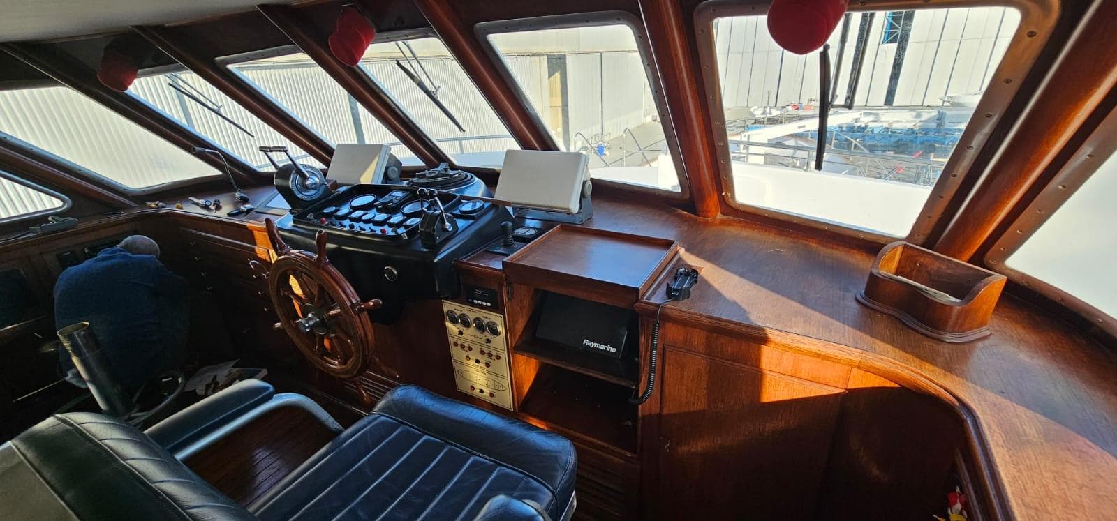 Interior of a 1972 Benetti 33 yacht cockpit with wooden dashboard and steering wheel.
